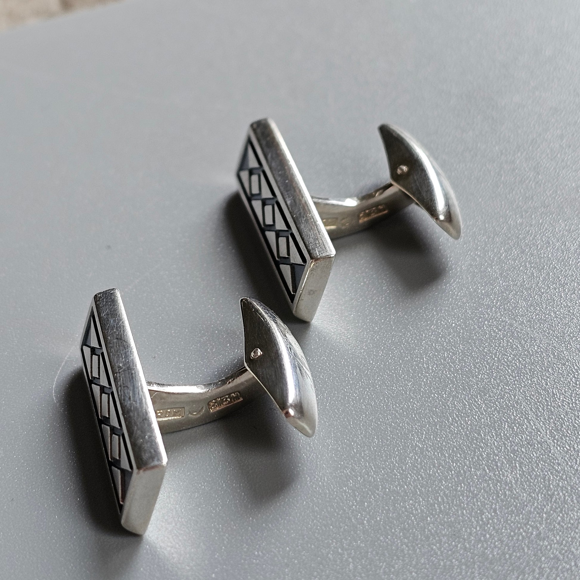 Pair of silver rectangular cufflinks with geometric patterns.