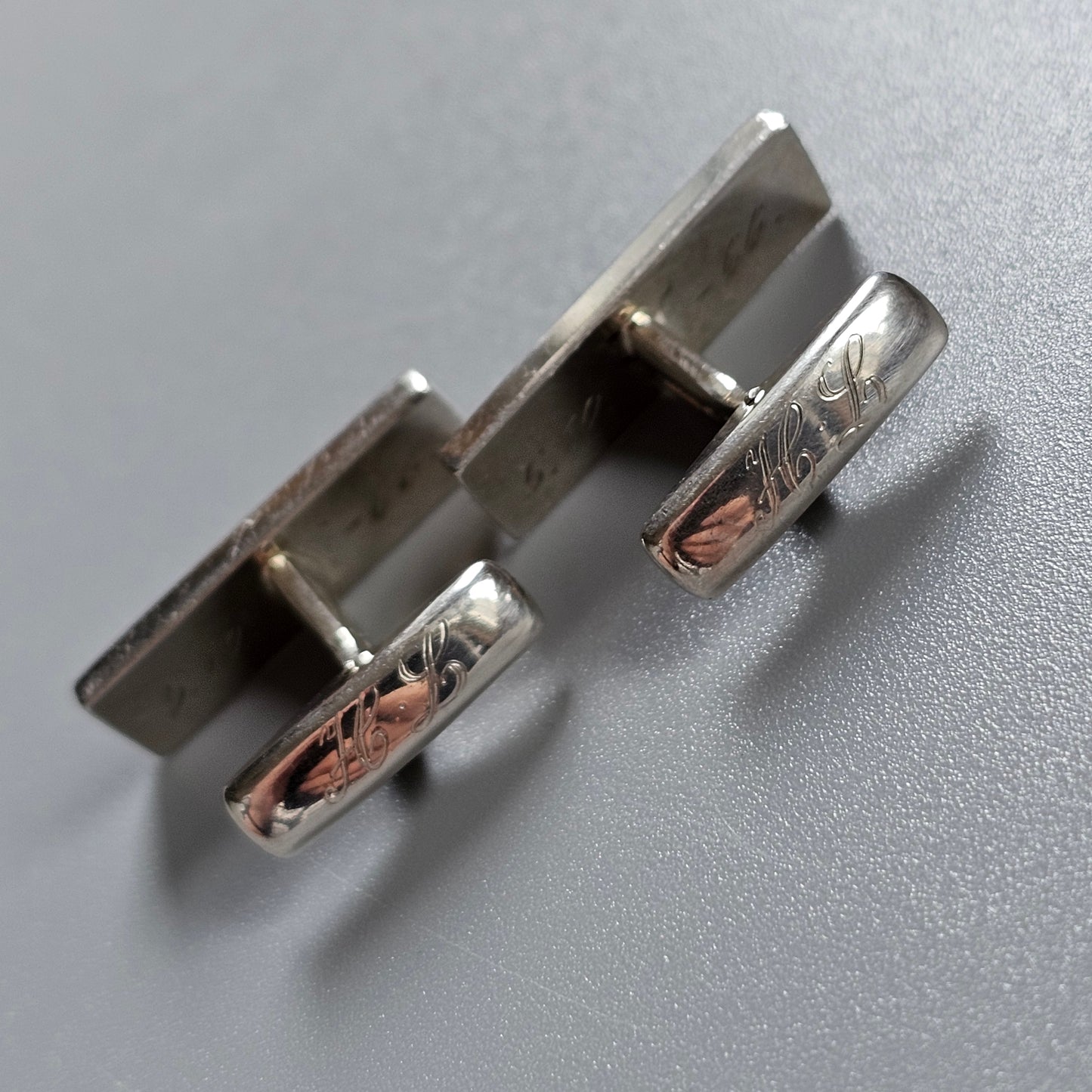 Pair of silver cufflinks with decorative engraving on the sides.