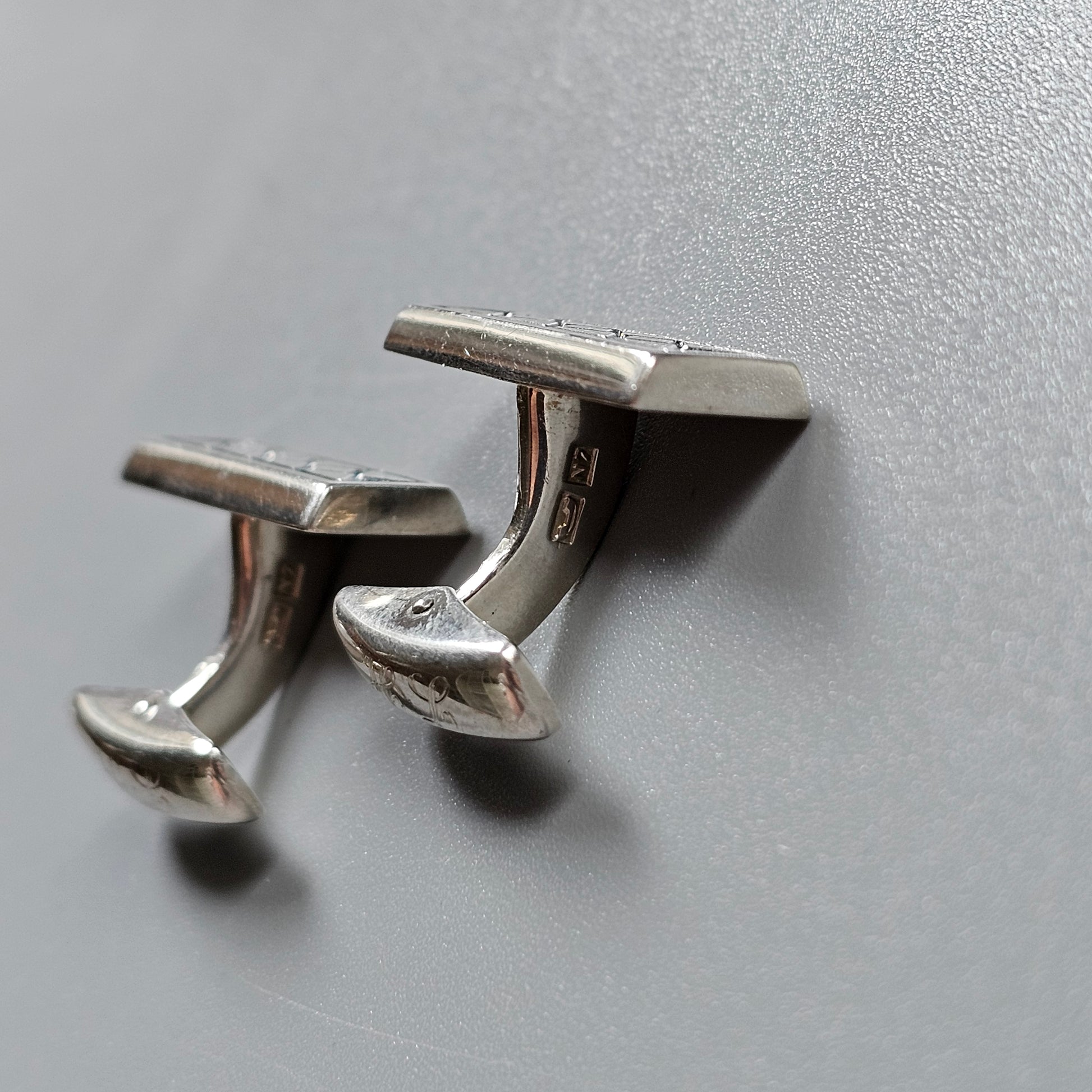 Pair of silver cufflinks with a curved, elongated design.