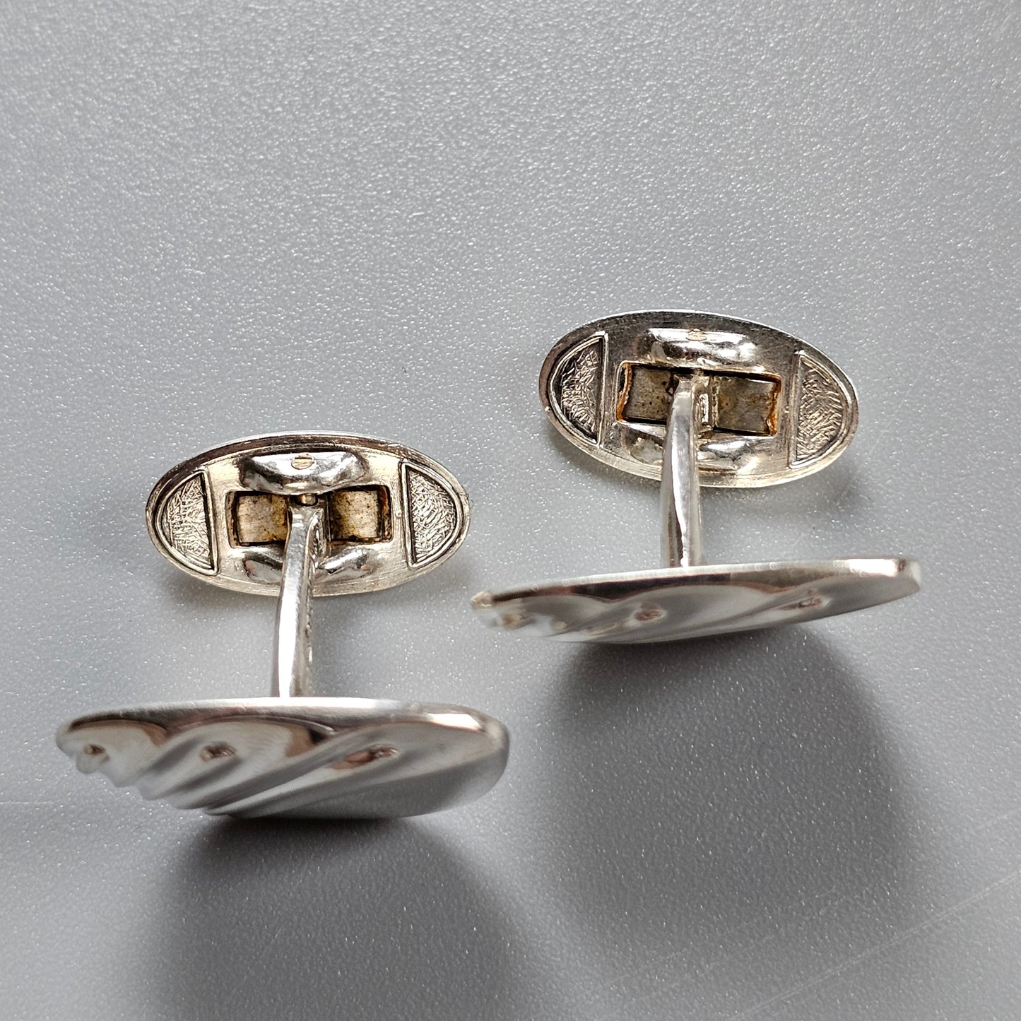 Pair of silver cufflinks with a twisted rope-like design.