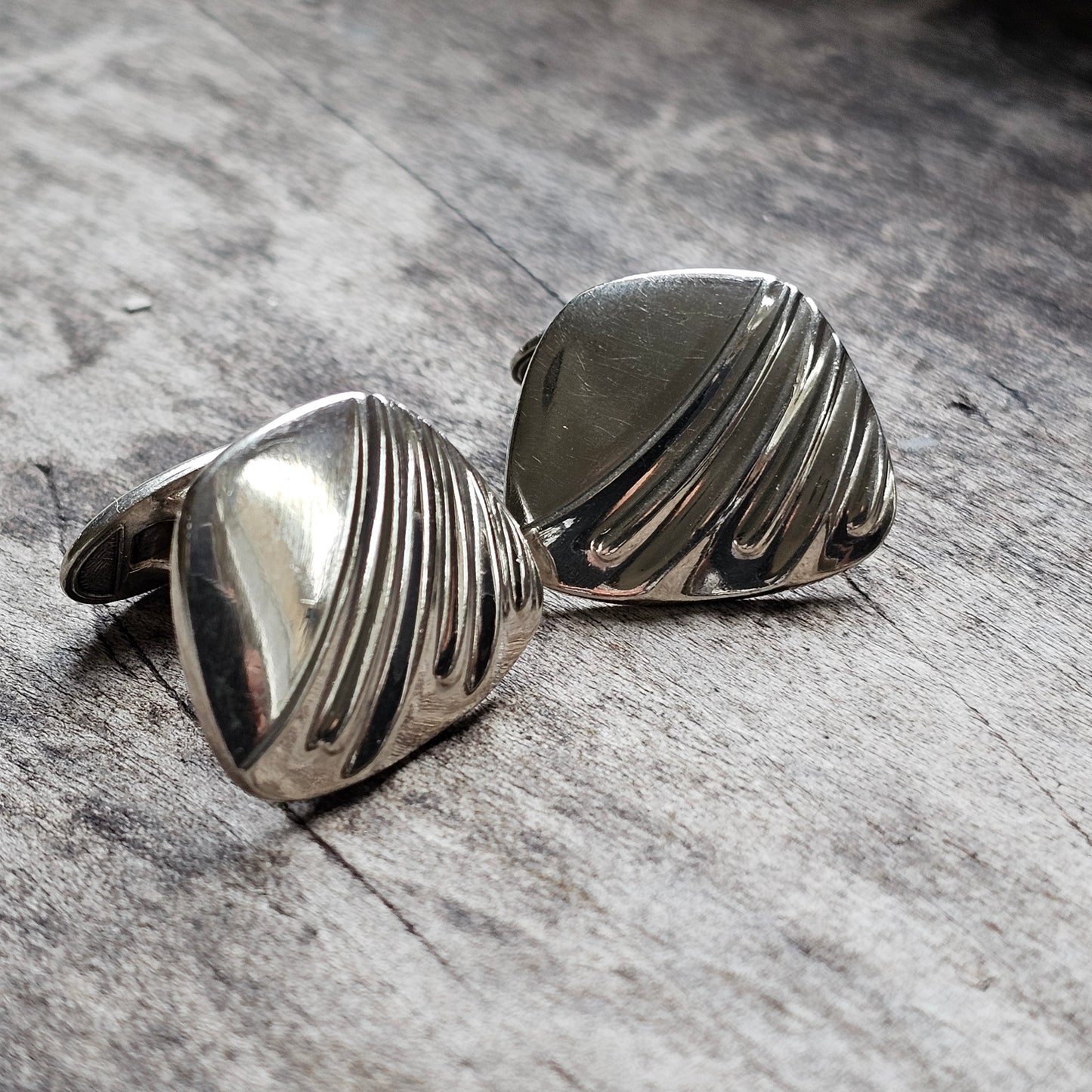 Pair of silver cufflinks with a ridged, shell-like design.