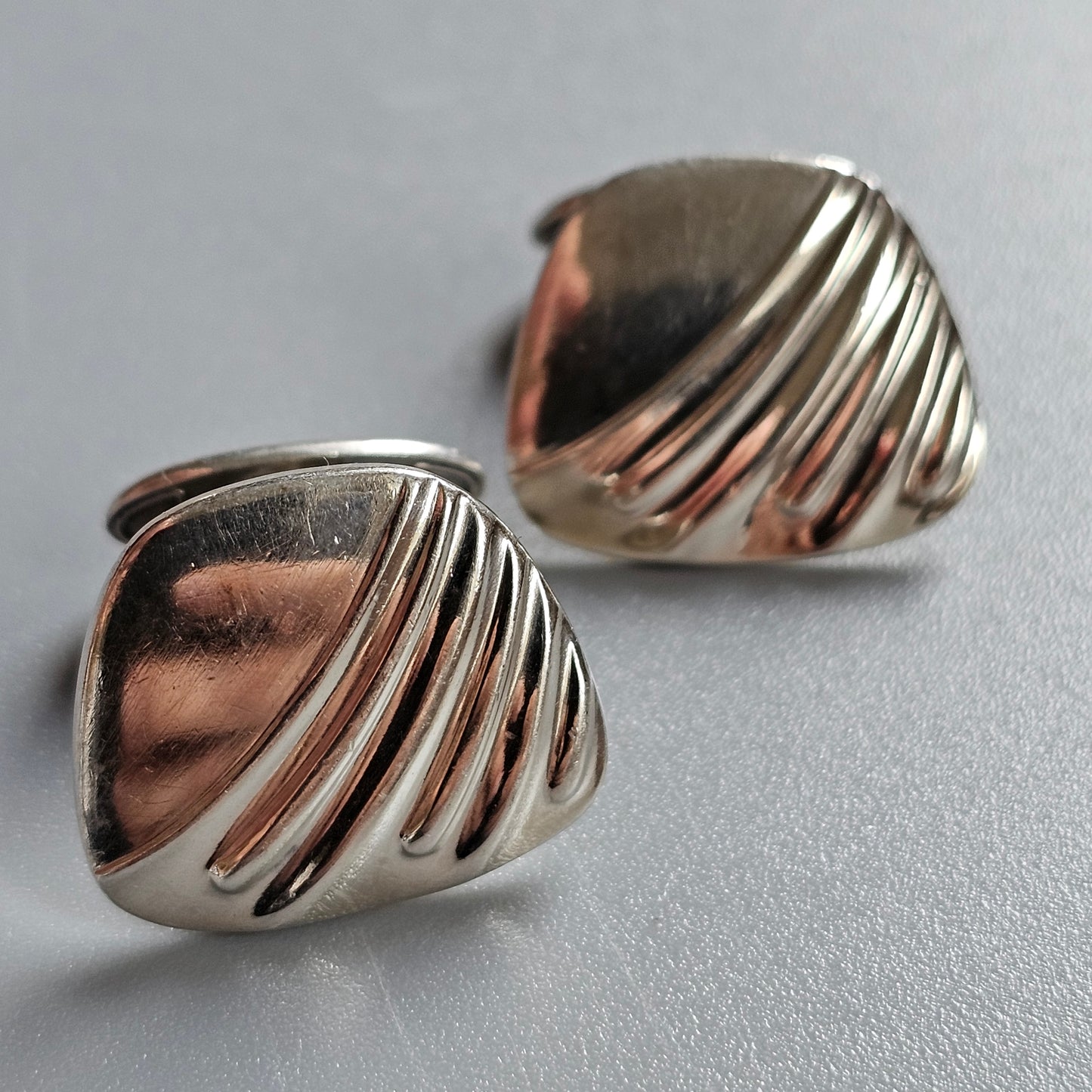 Pair of silver cufflinks with a ridged, shell-like design.