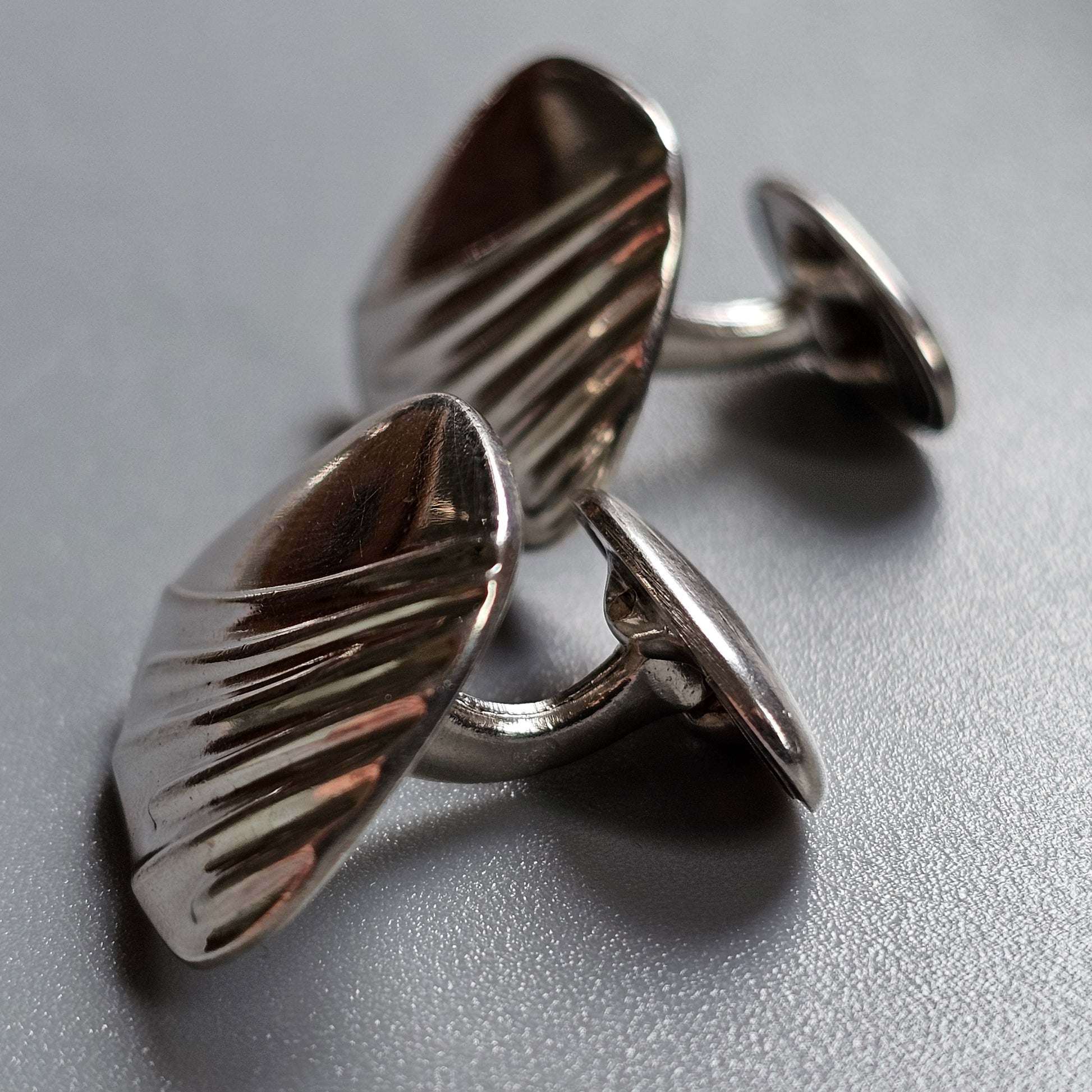 Pair of silver cufflinks with a ribbed oval design.