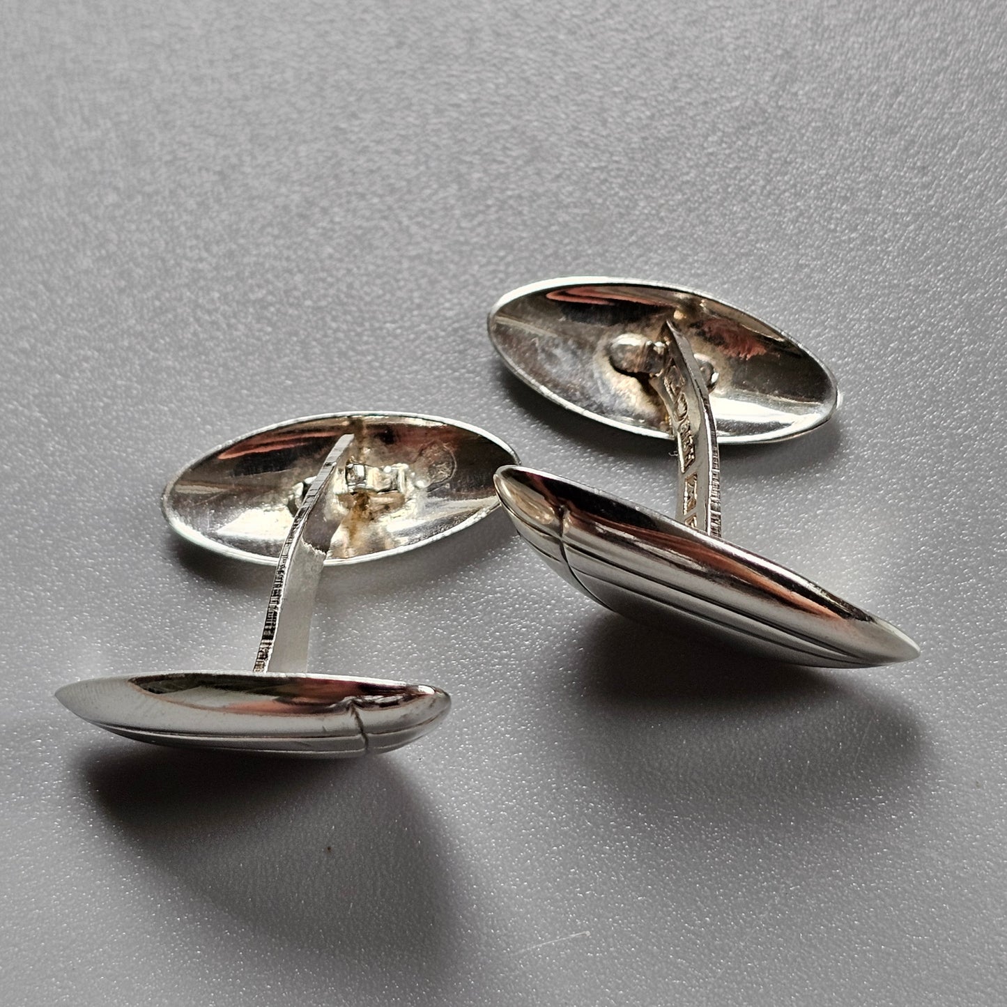 Pair of silver oval cufflinks with connecting chains.