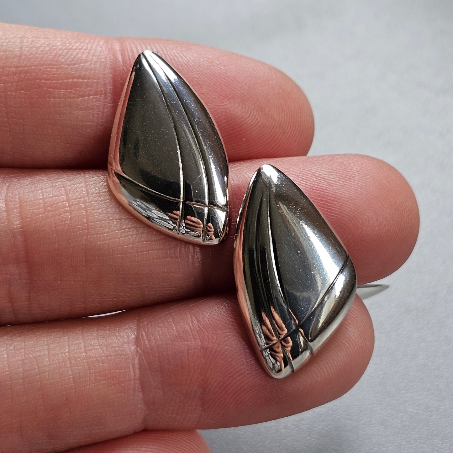 Pair of silver teardrop-shaped earrings with engraved lines.