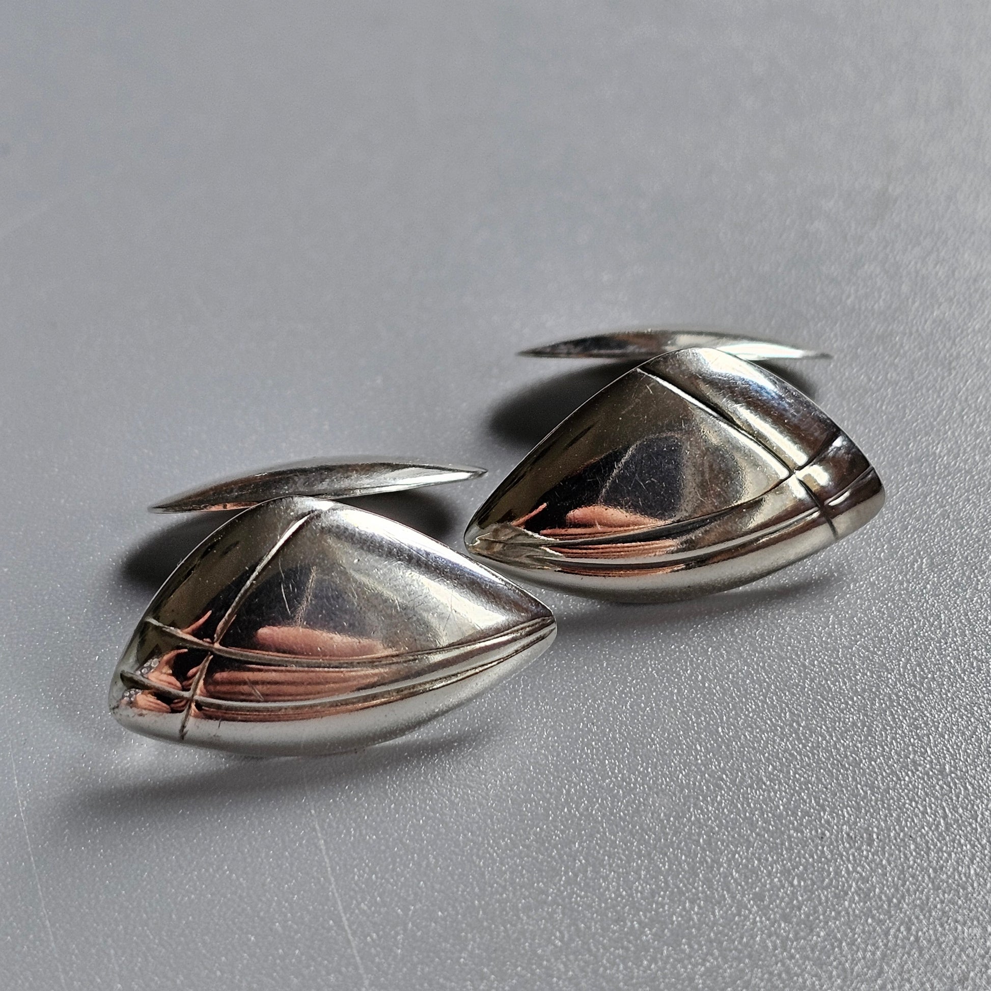 Pair of teardrop-shaped silver cufflinks with copper-colored accents.