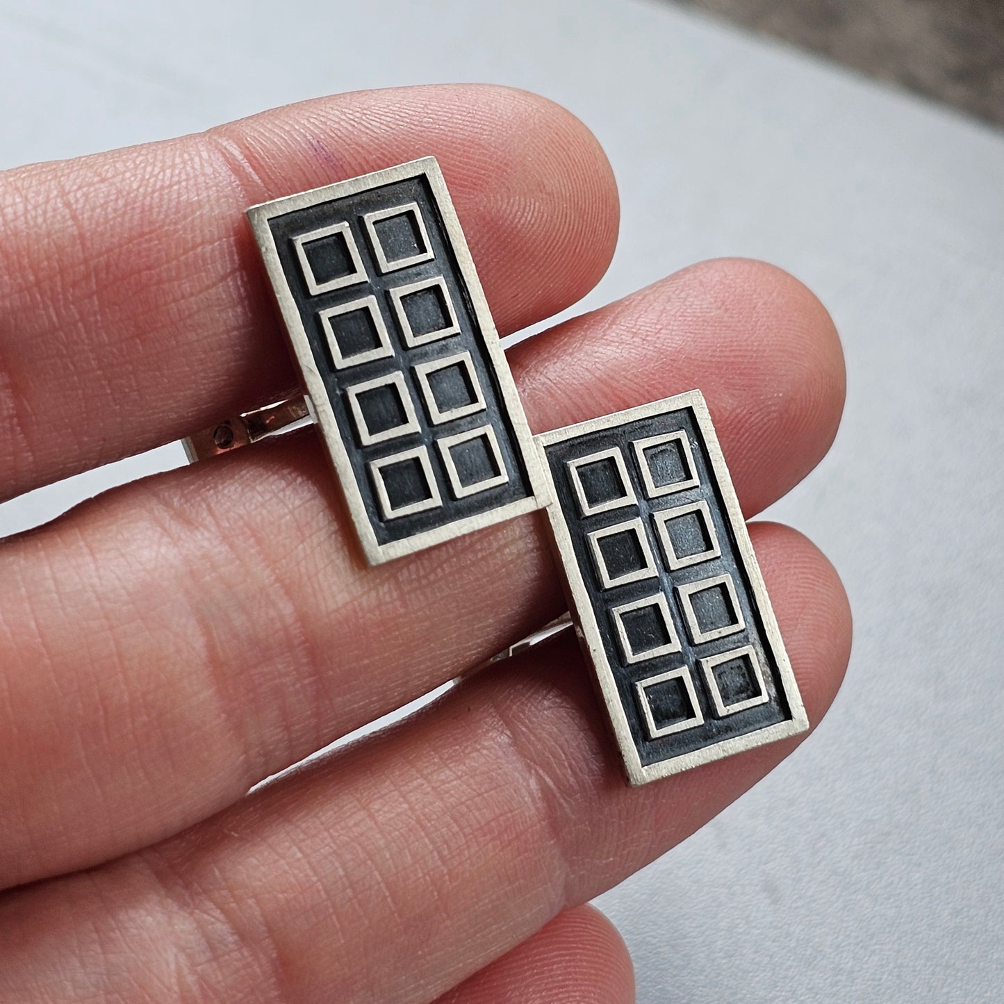 Pair of rectangular silver earrings with a geometric grid pattern.