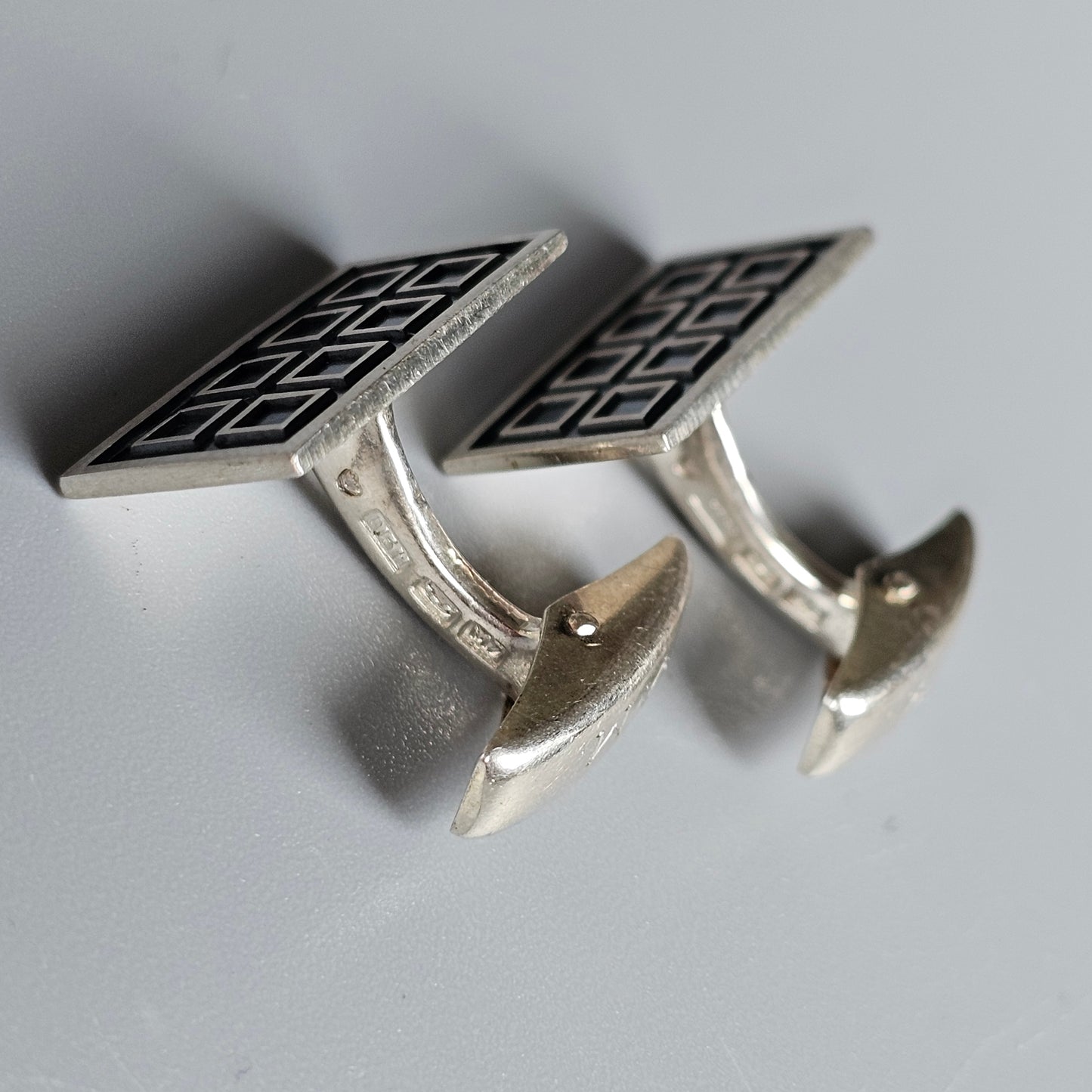 Pair of silver cufflinks with a geometric pattern design.