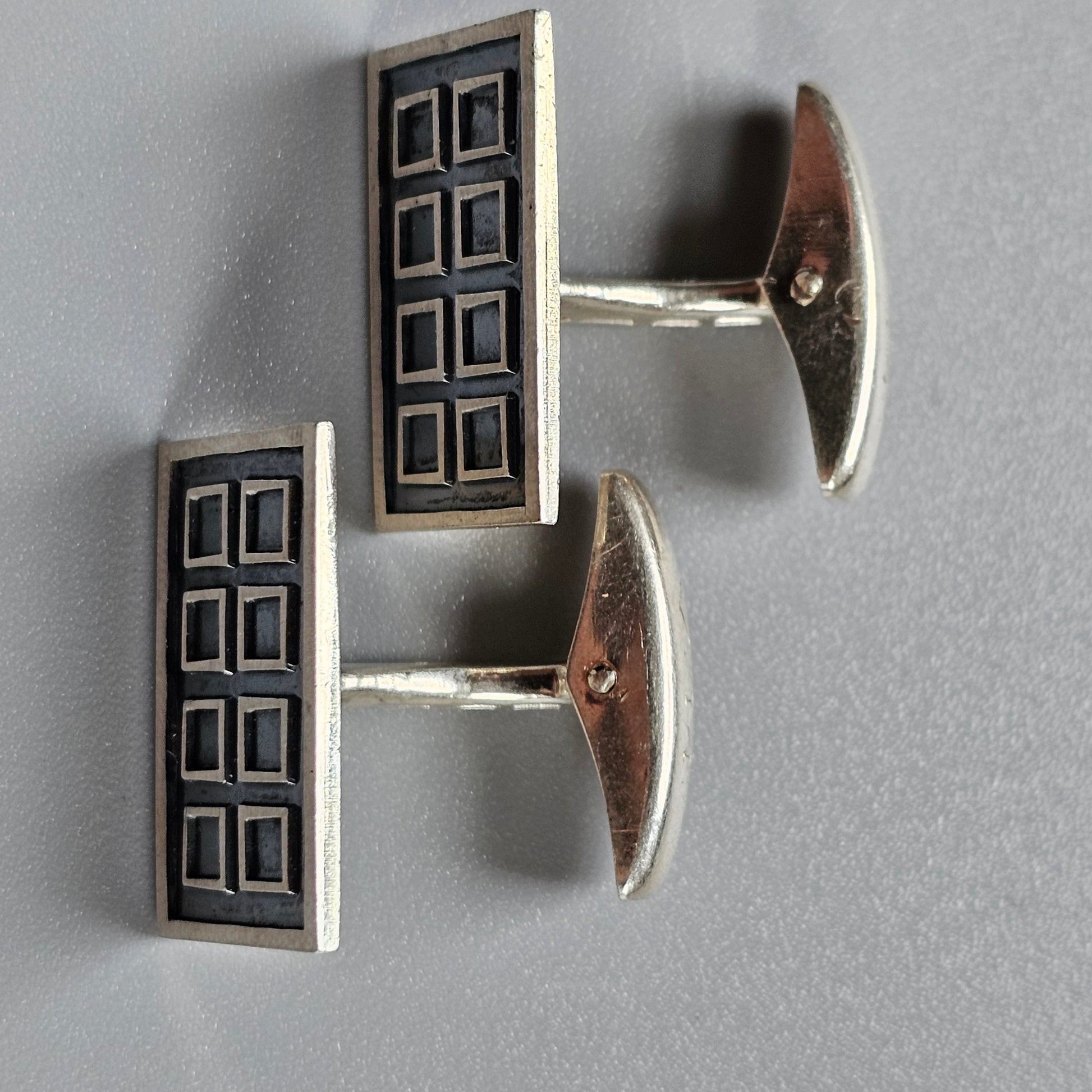 Pair of rectangular silver and black cufflinks with a geometric pattern.