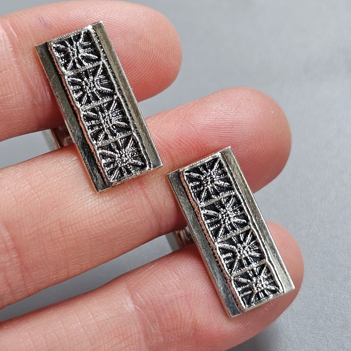 Pair of rectangular metal jewelry components with intricate floral filigree designs.