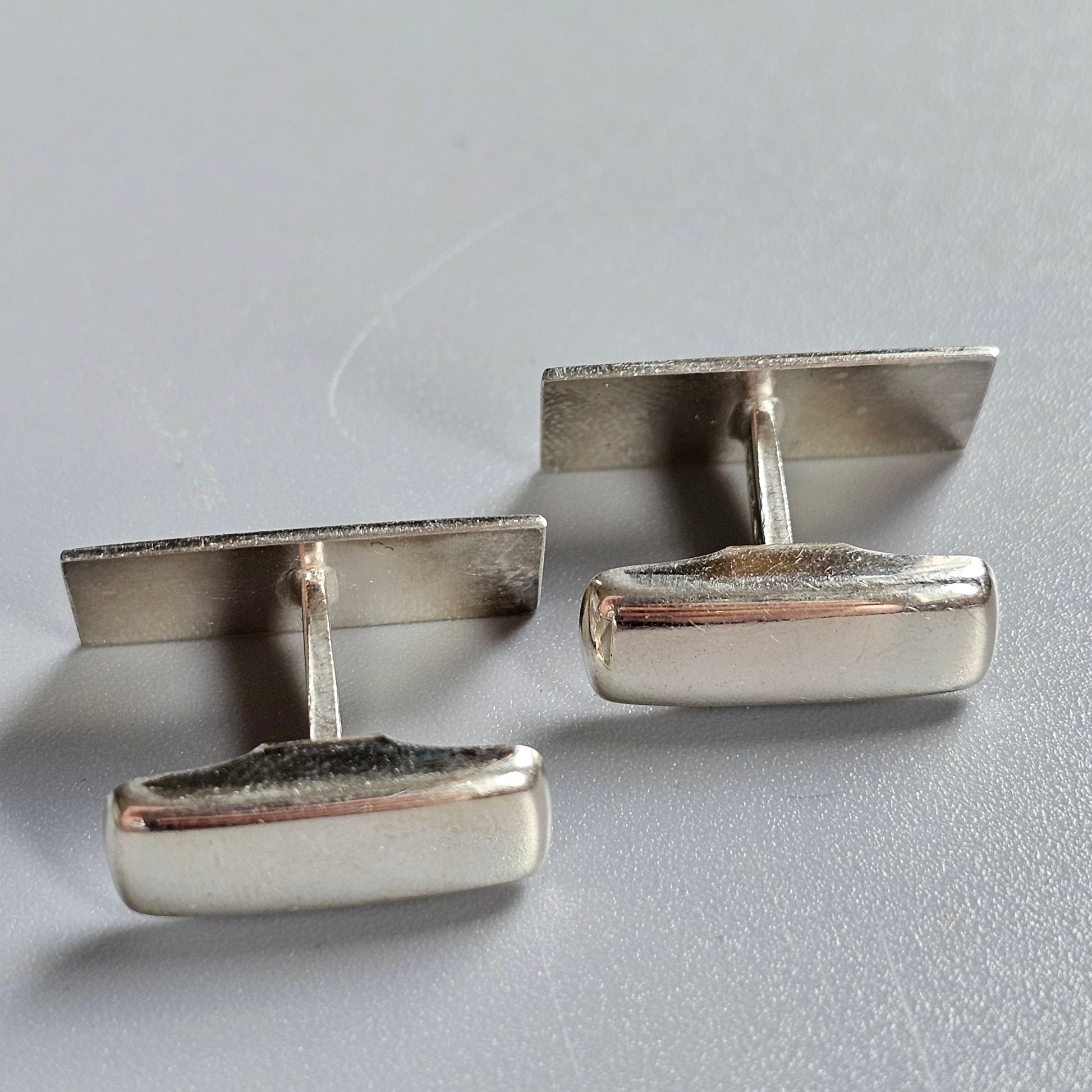 Pair of silver rectangular cufflinks with smooth, polished surfaces.