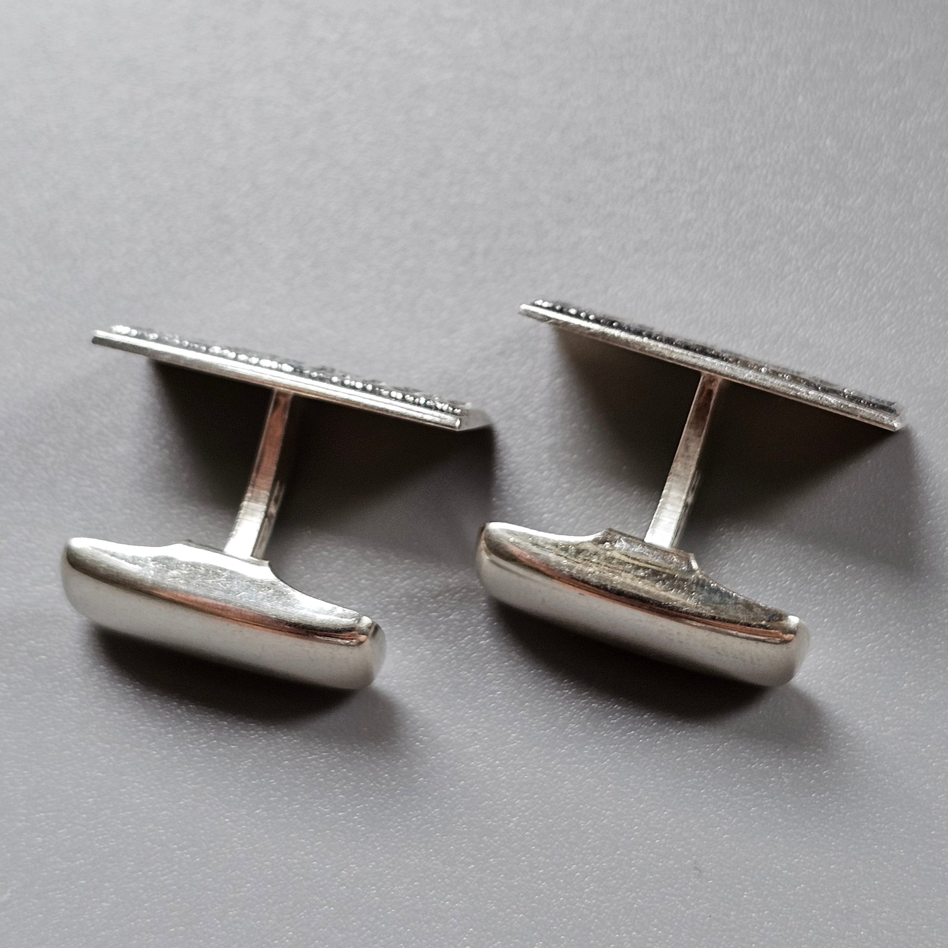 Pair of silver oval cufflinks with textured surfaces.