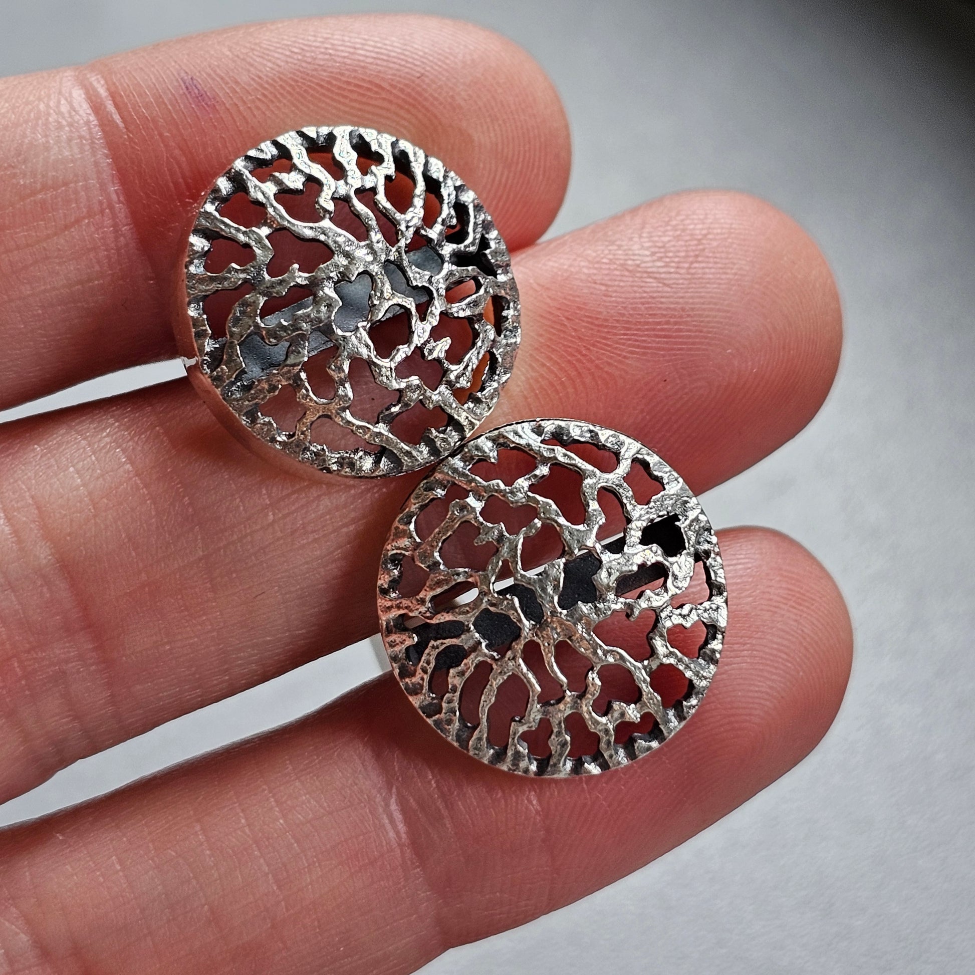 Pair of intricate silver filigree earrings with circular designs.