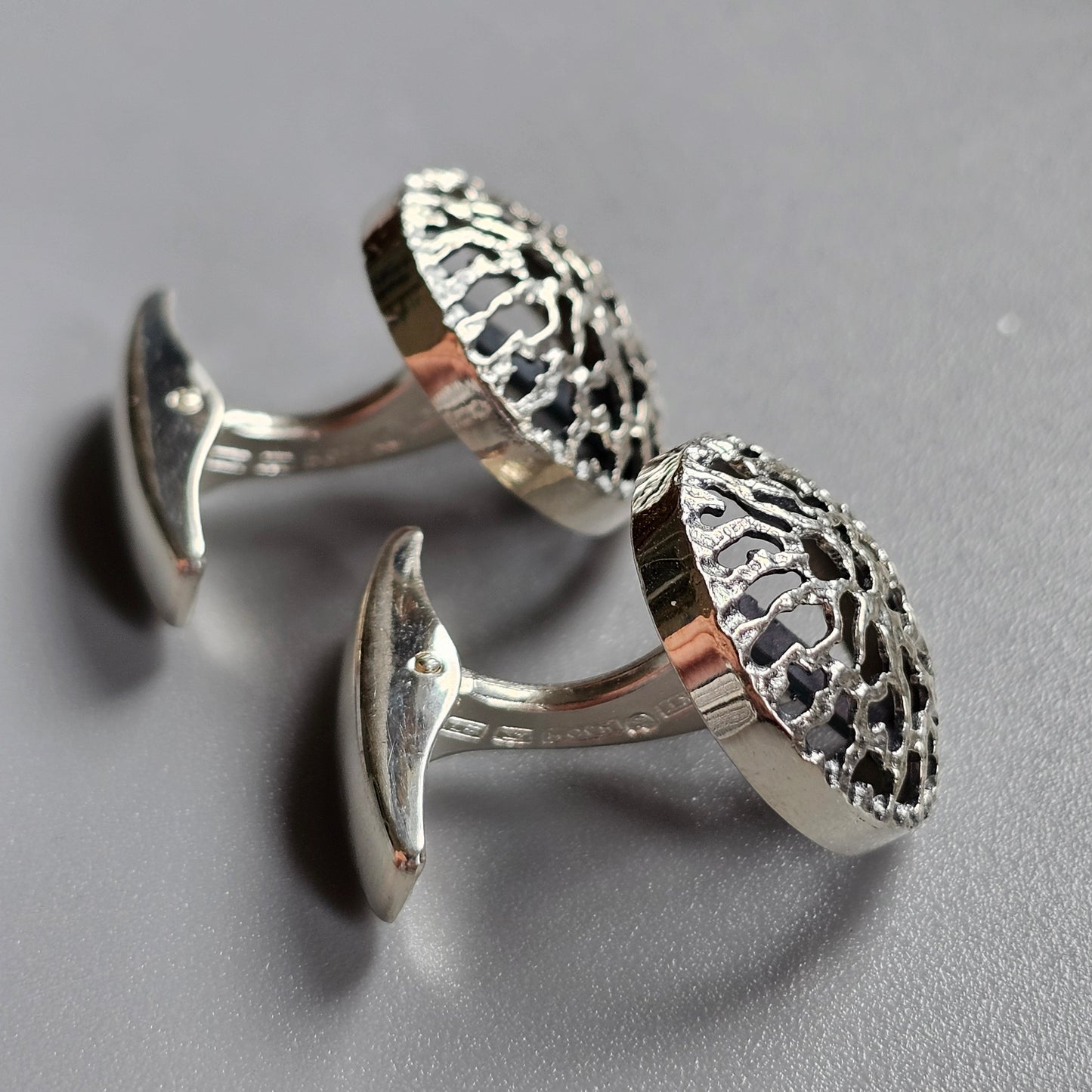 Pair of ornate silver cufflinks with intricate filigree designs.