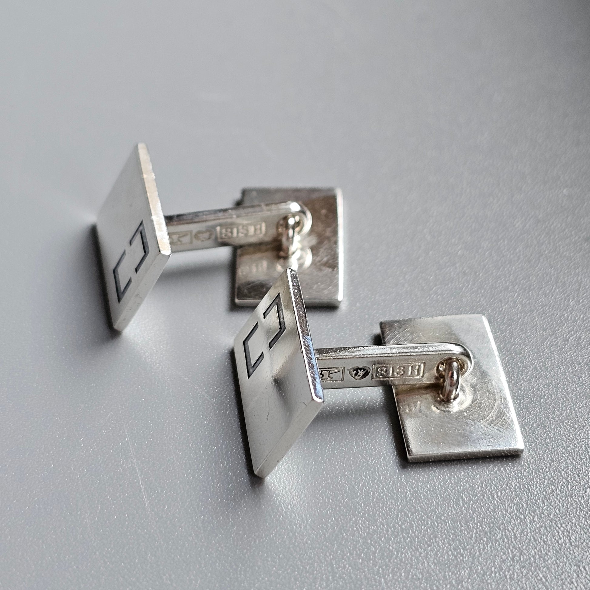 Pair of silver square cufflinks with geometric designs.