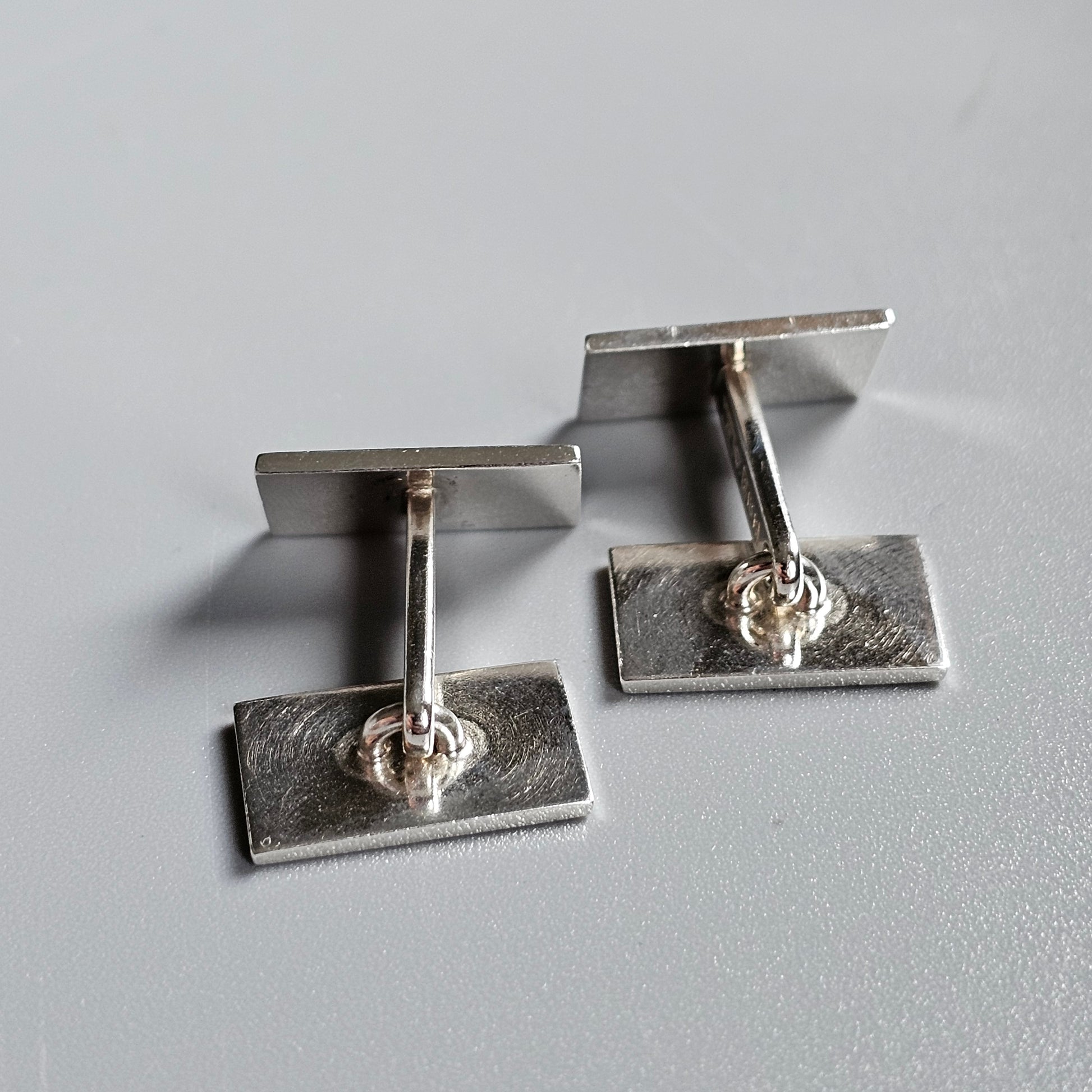 Pair of silver cufflinks with rectangular bases and small gemstones.