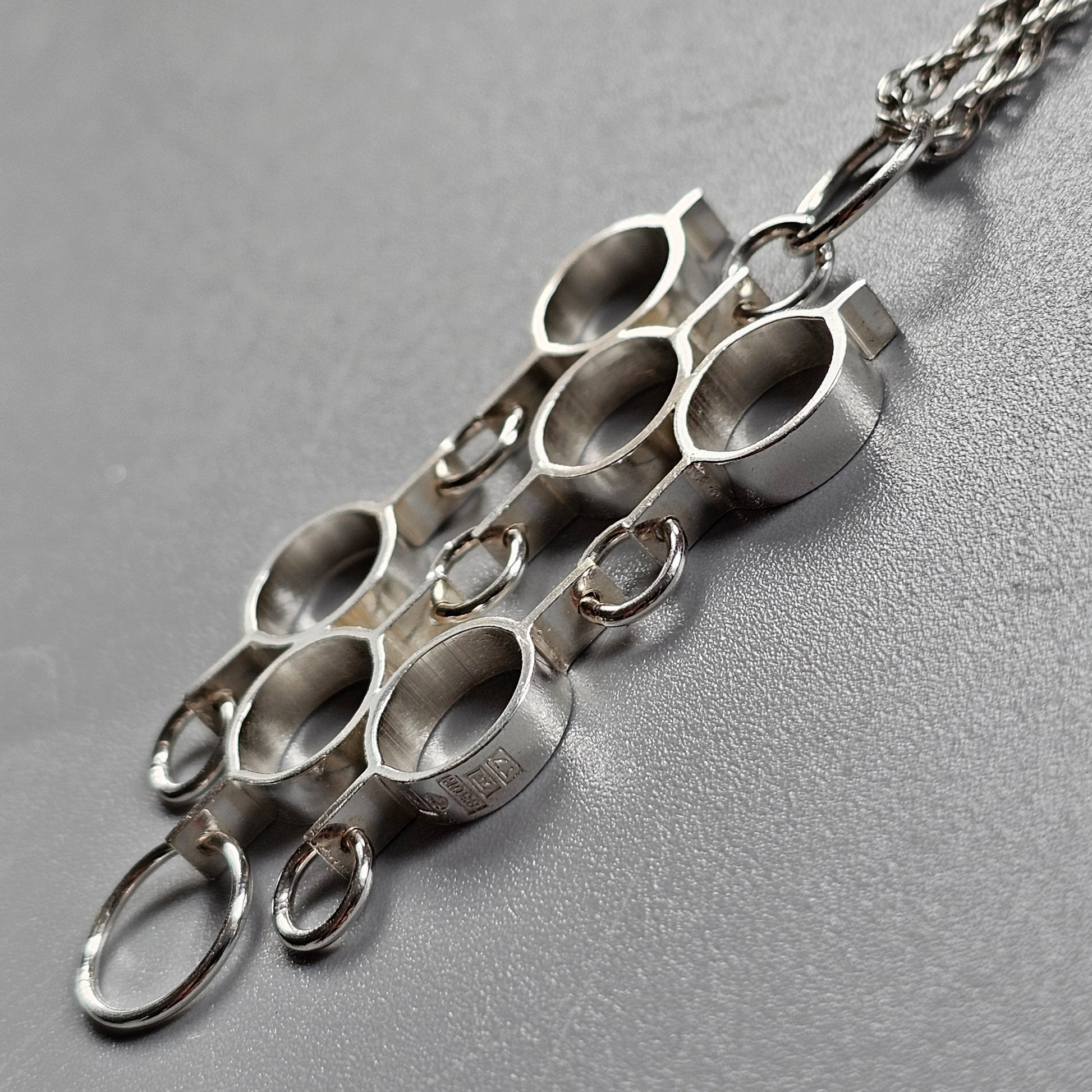 Silver pendant necklace with multiple circular openings arranged in a geometric pattern.