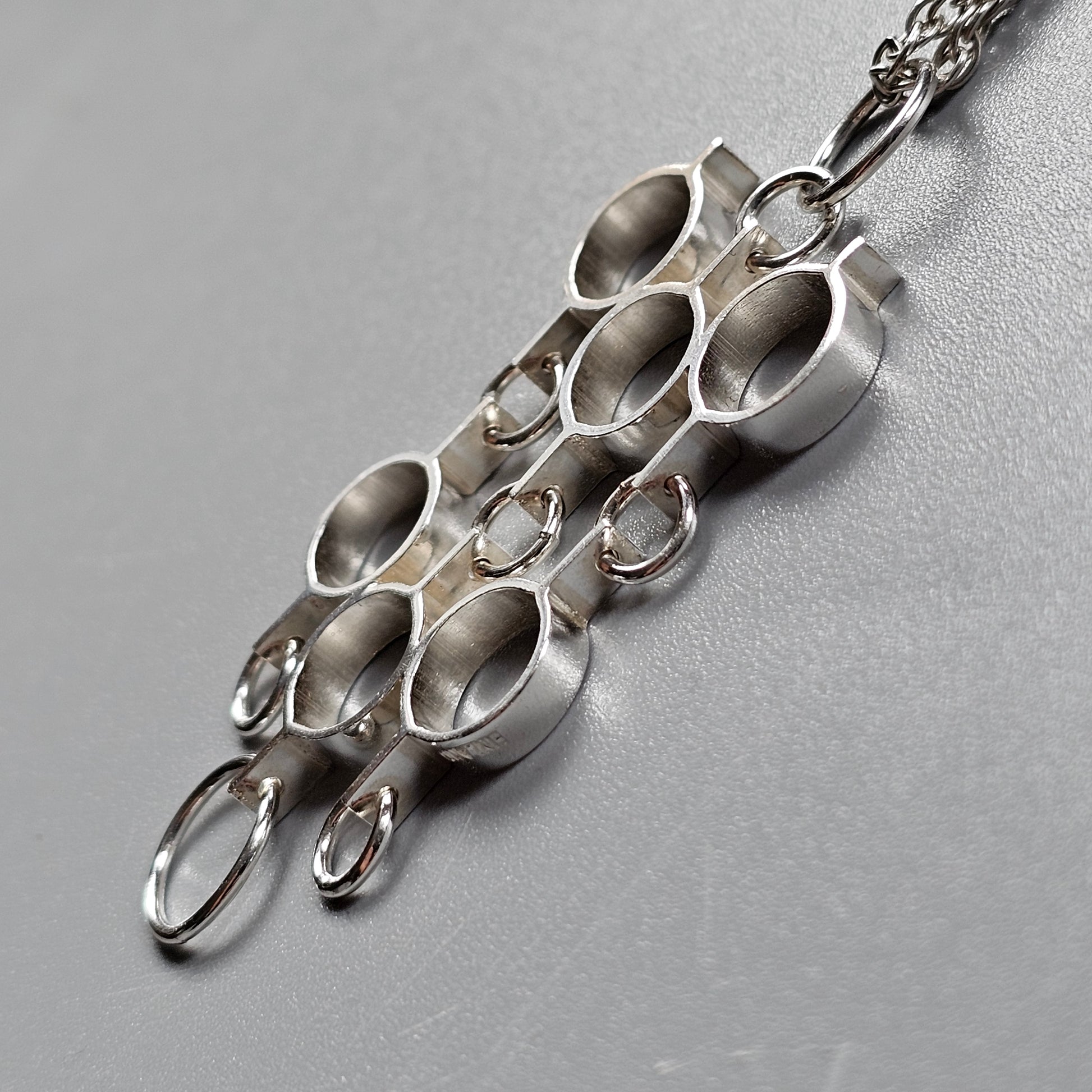 Silver pendant necklace featuring multiple oval-shaped loops arranged in a cluster.