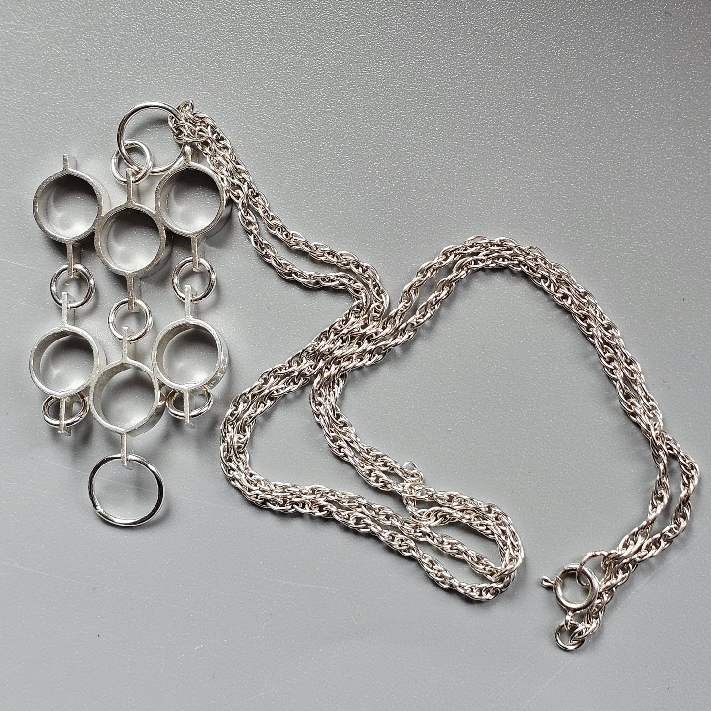 Silver pendant necklace featuring interconnected circular shapes.