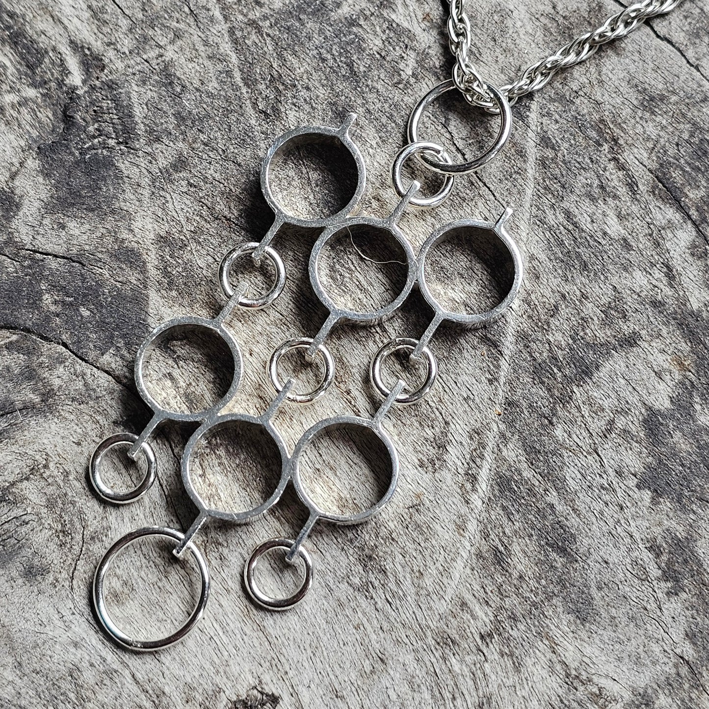 Silver pendant necklace with multiple interconnected circular rings.