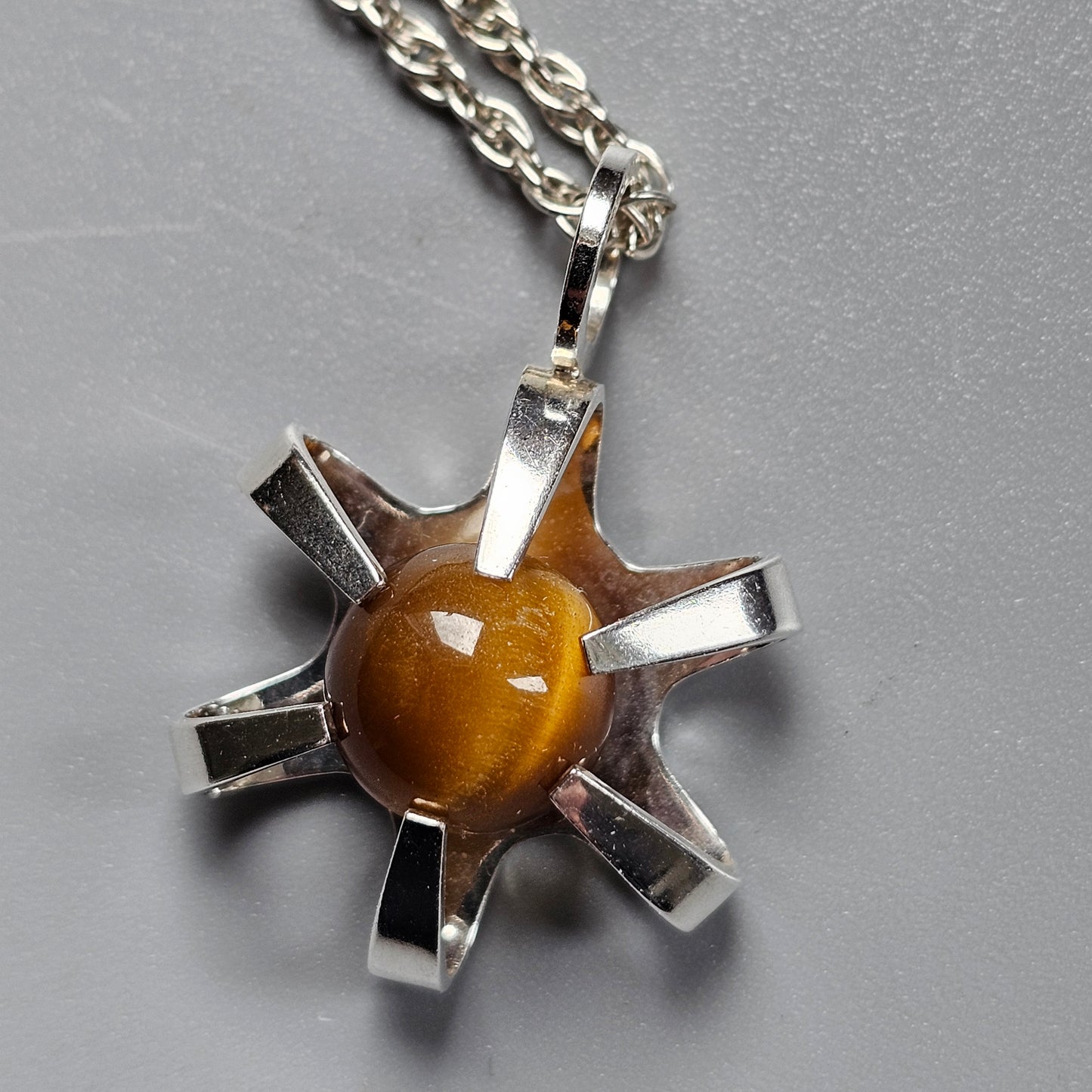 Silver star-shaped pendant with an amber-colored gemstone at its center, hanging from a chain.