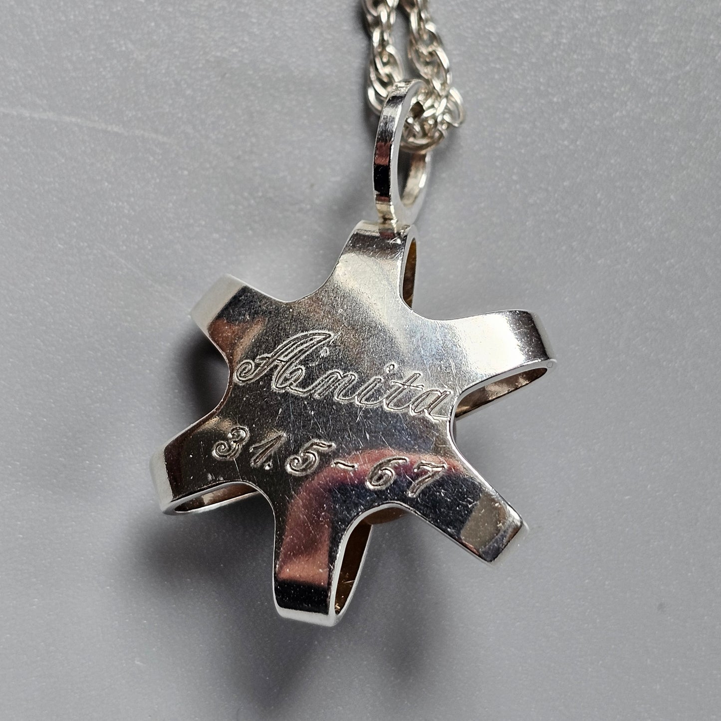 Silver star-shaped pendant engraved with ’Anita 2007’’ on a chain necklace.