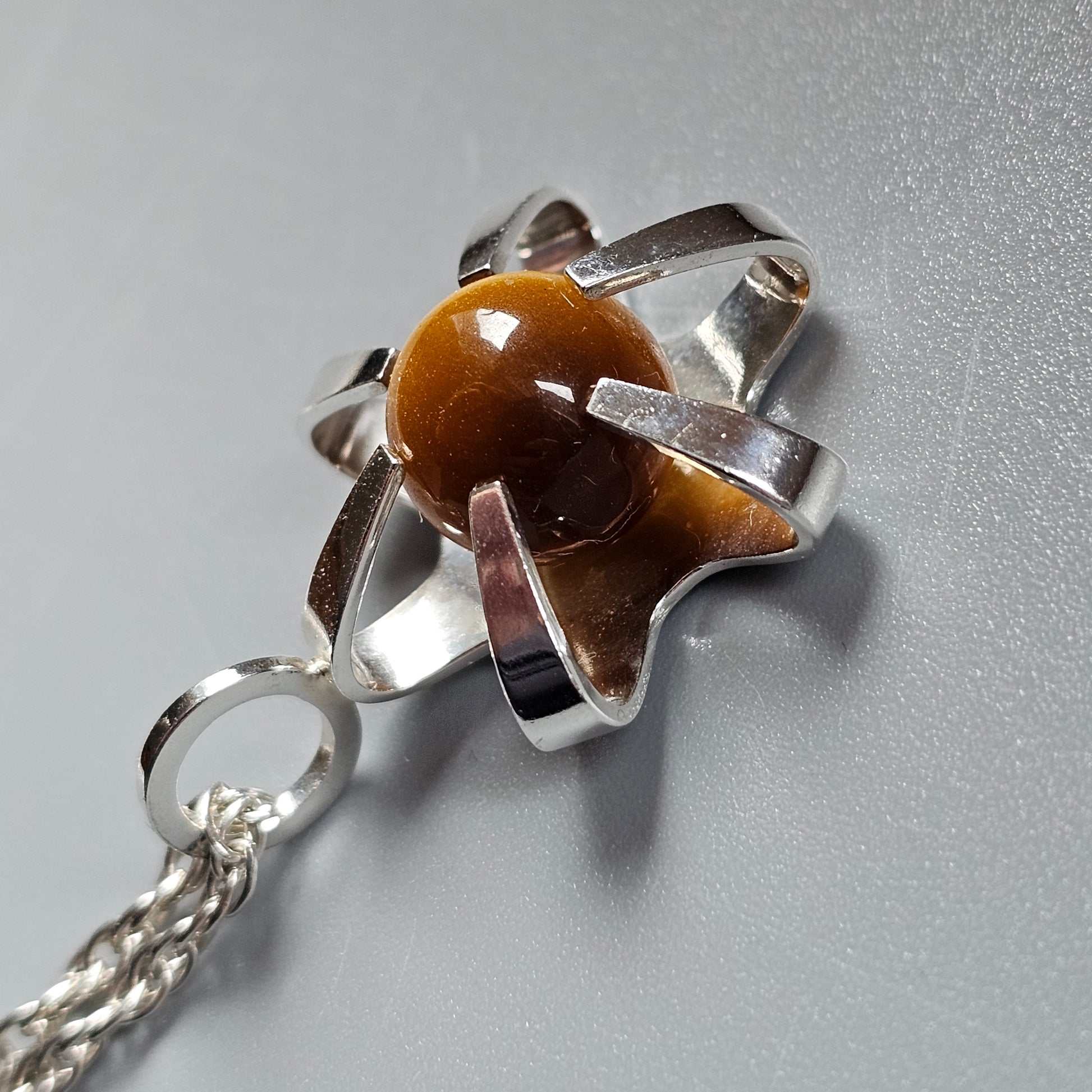 Silver pendant featuring a star-shaped setting with a brown gemstone or bead at its center.