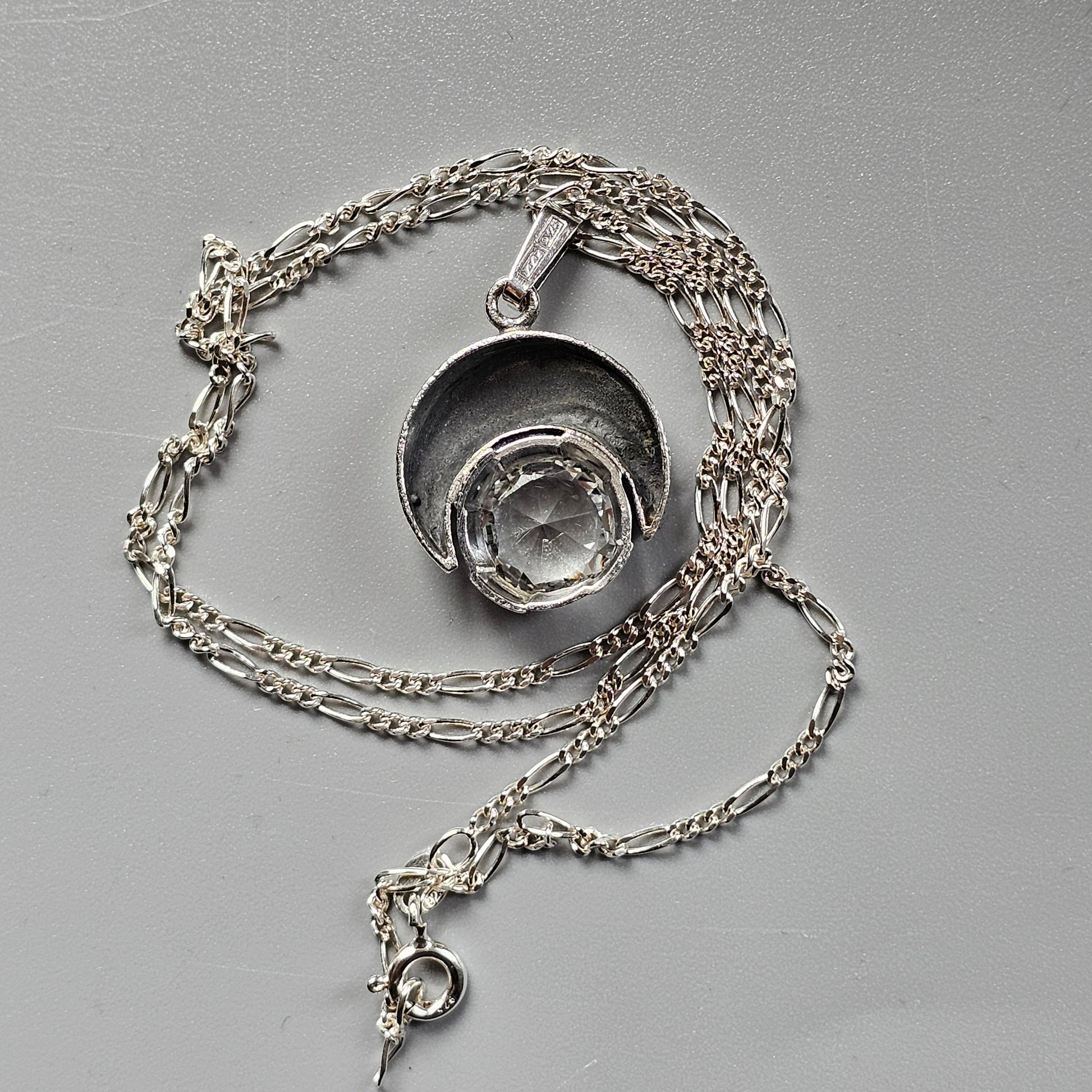 Silver pendant necklace featuring a circular charm with a concentric spiral design.