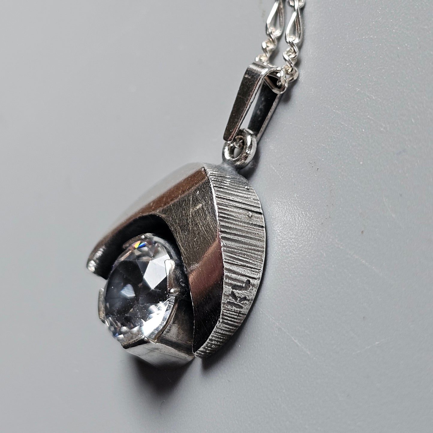 Silver pendant necklace featuring a stylized eye design with a clear gemstone.