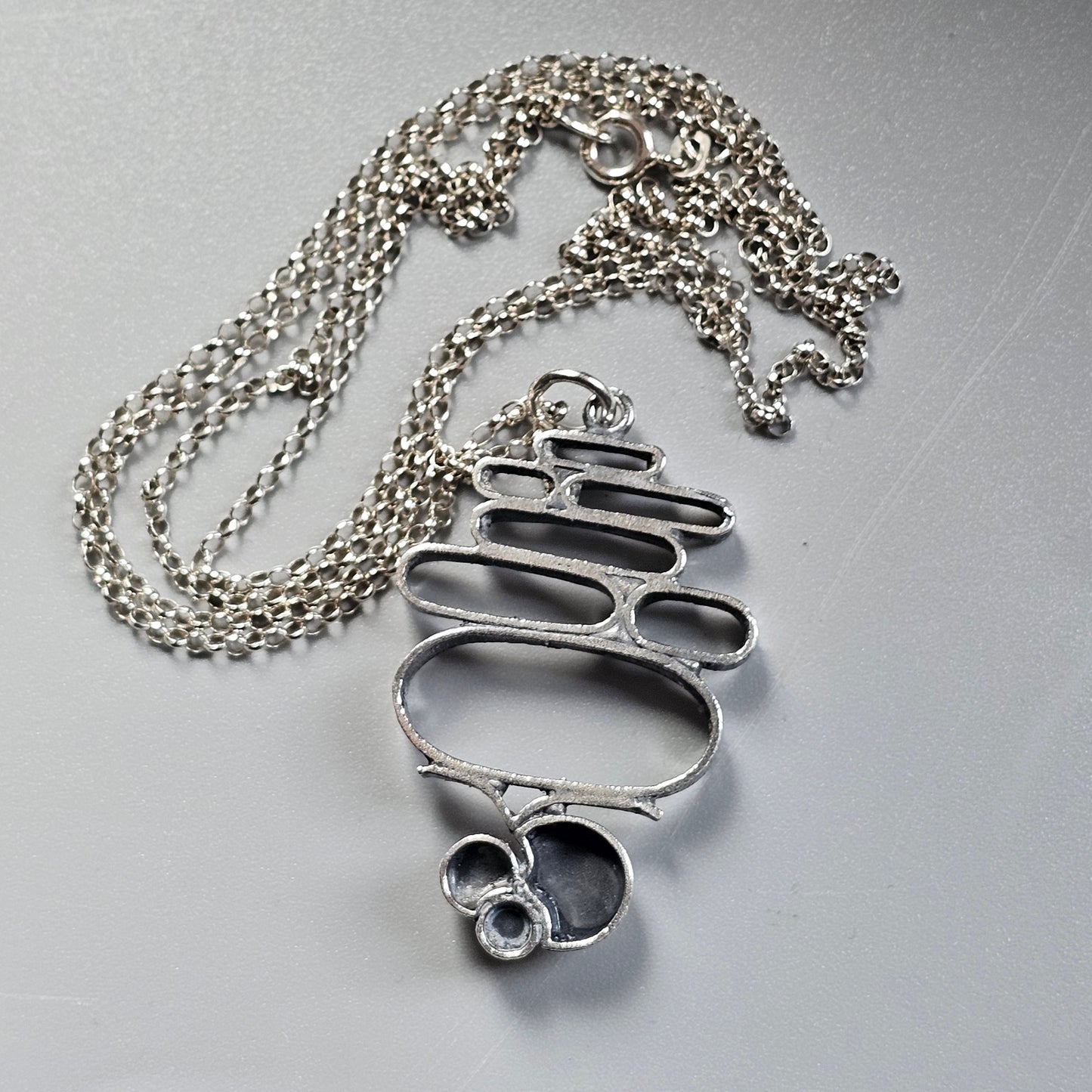 Abstract silver pendant with organic curved shapes on a chain necklace.