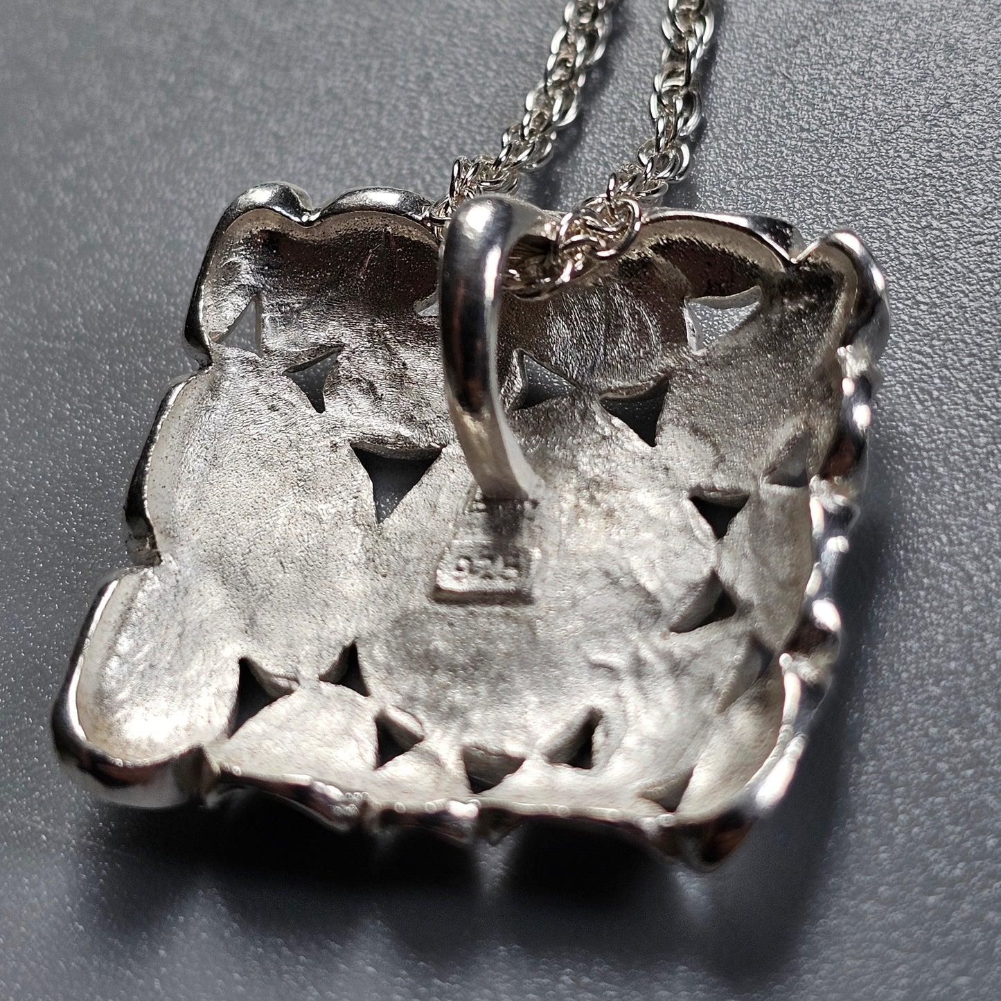 Square silver pendant with a textured, crystalline surface on a chain necklace.