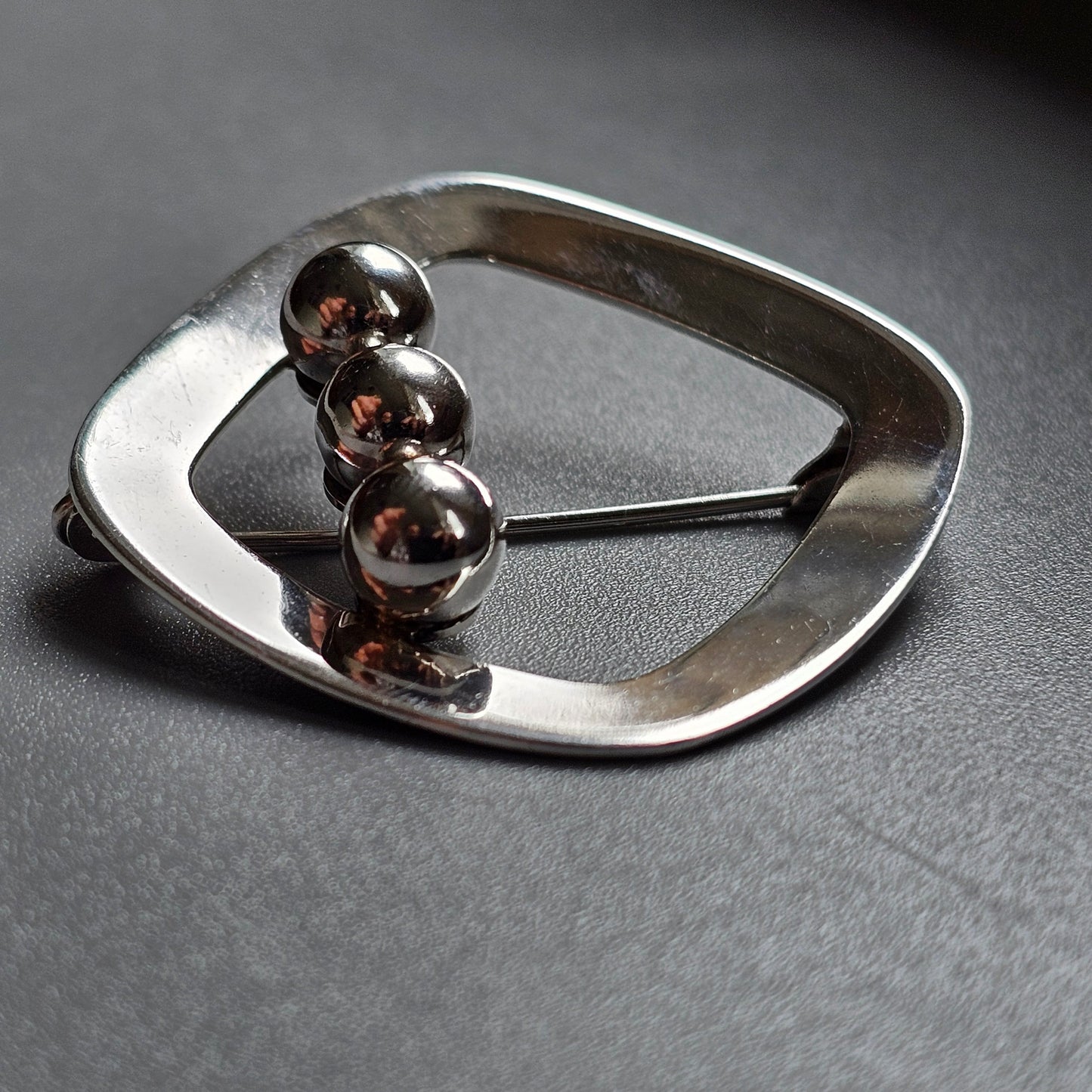 Modernist silver brooch with four spherical beads arranged in a curved line.