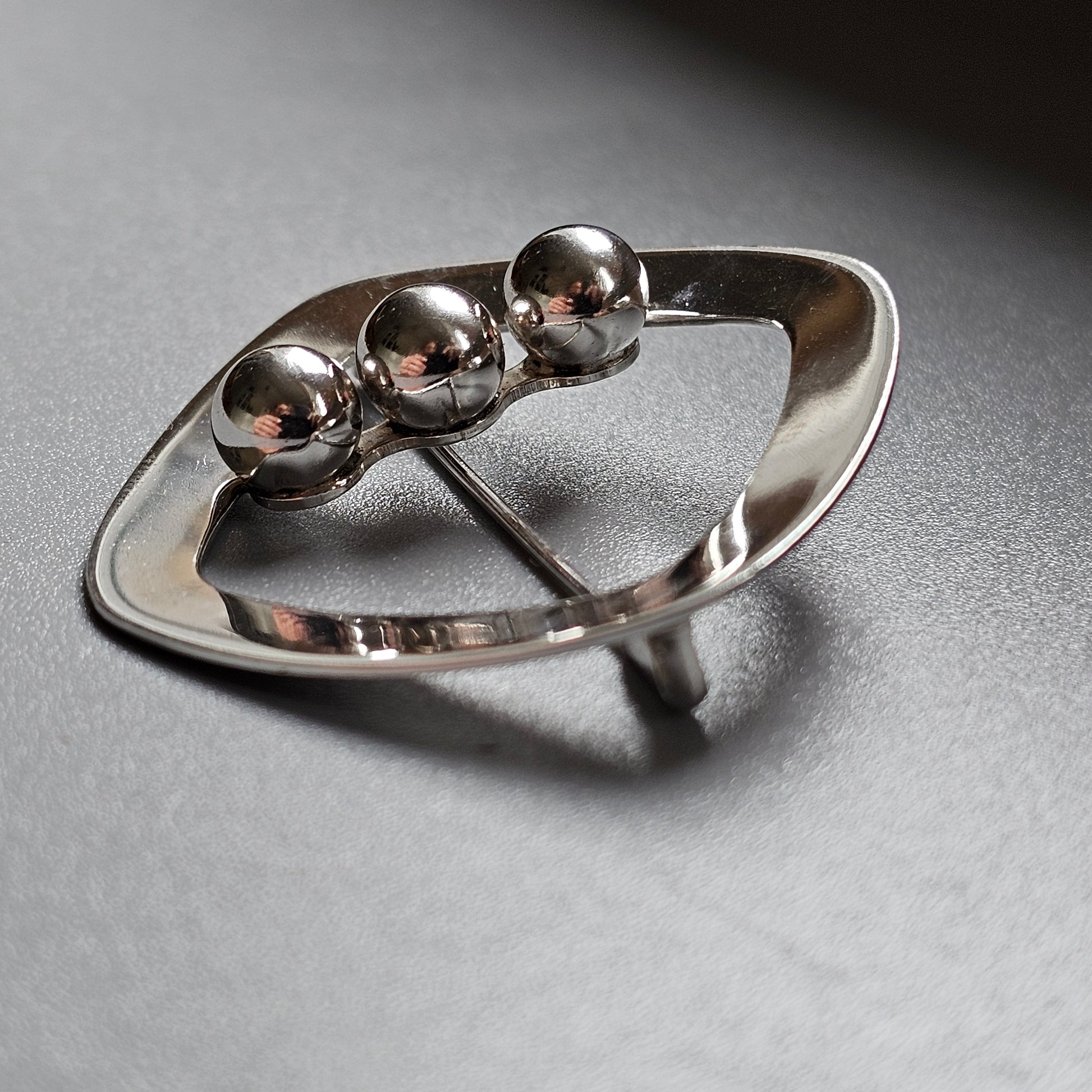 Silver ring with three spherical beads aligned on top.