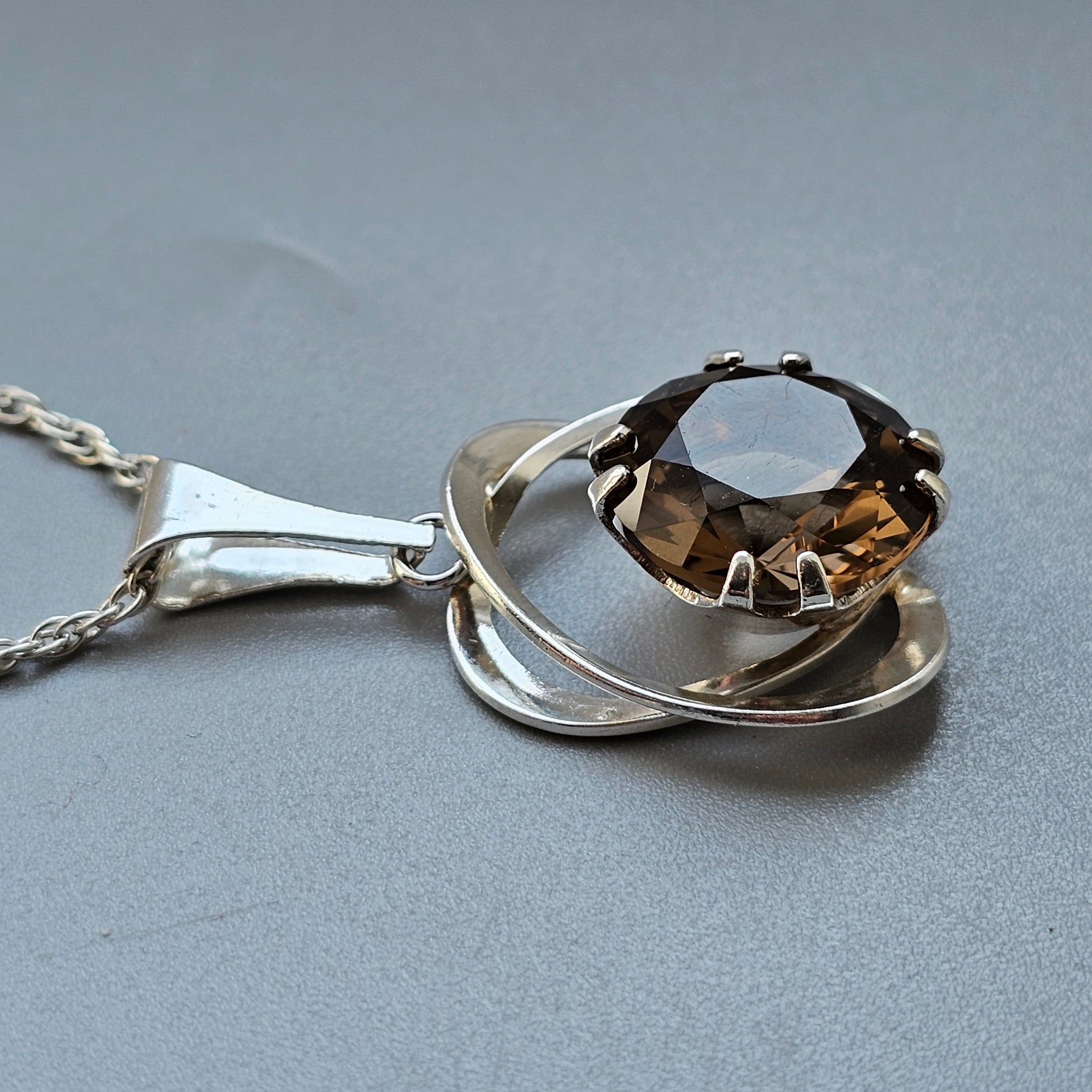 Silver pendant necklace featuring an oval-cut amber or topaz gemstone in a modern setting.