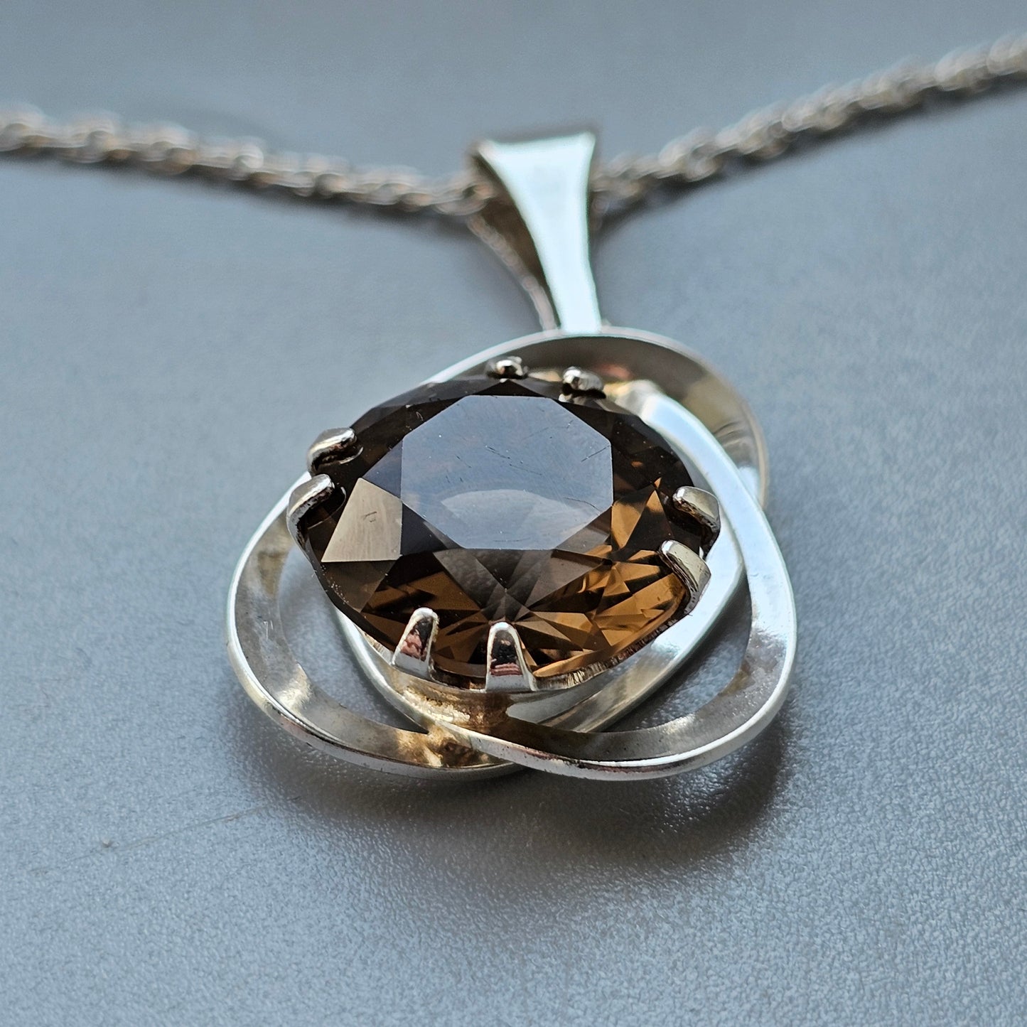 Silver pendant necklace featuring a round smoky quartz gemstone set in an abstract, swirling design.