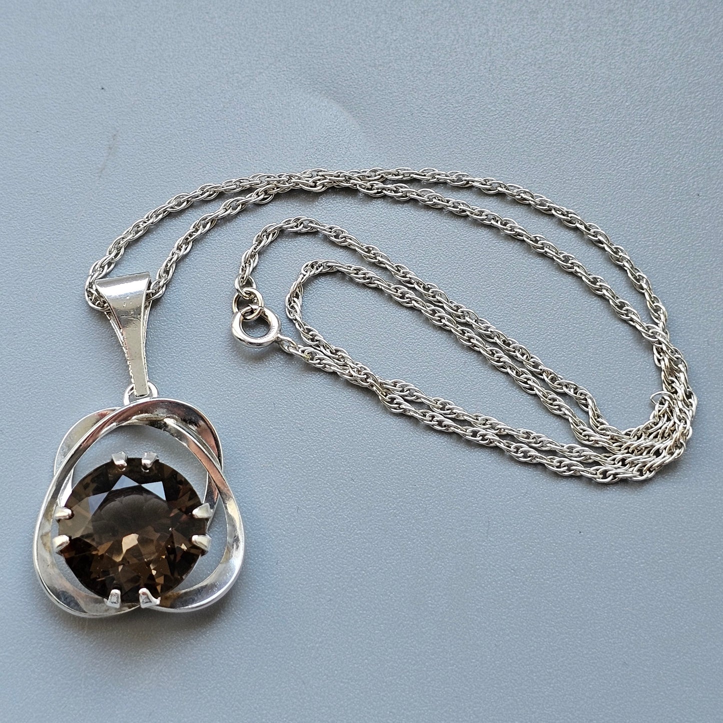 Silver pendant necklace featuring a smoky quartz gemstone set in a stylized floral or abstract design.