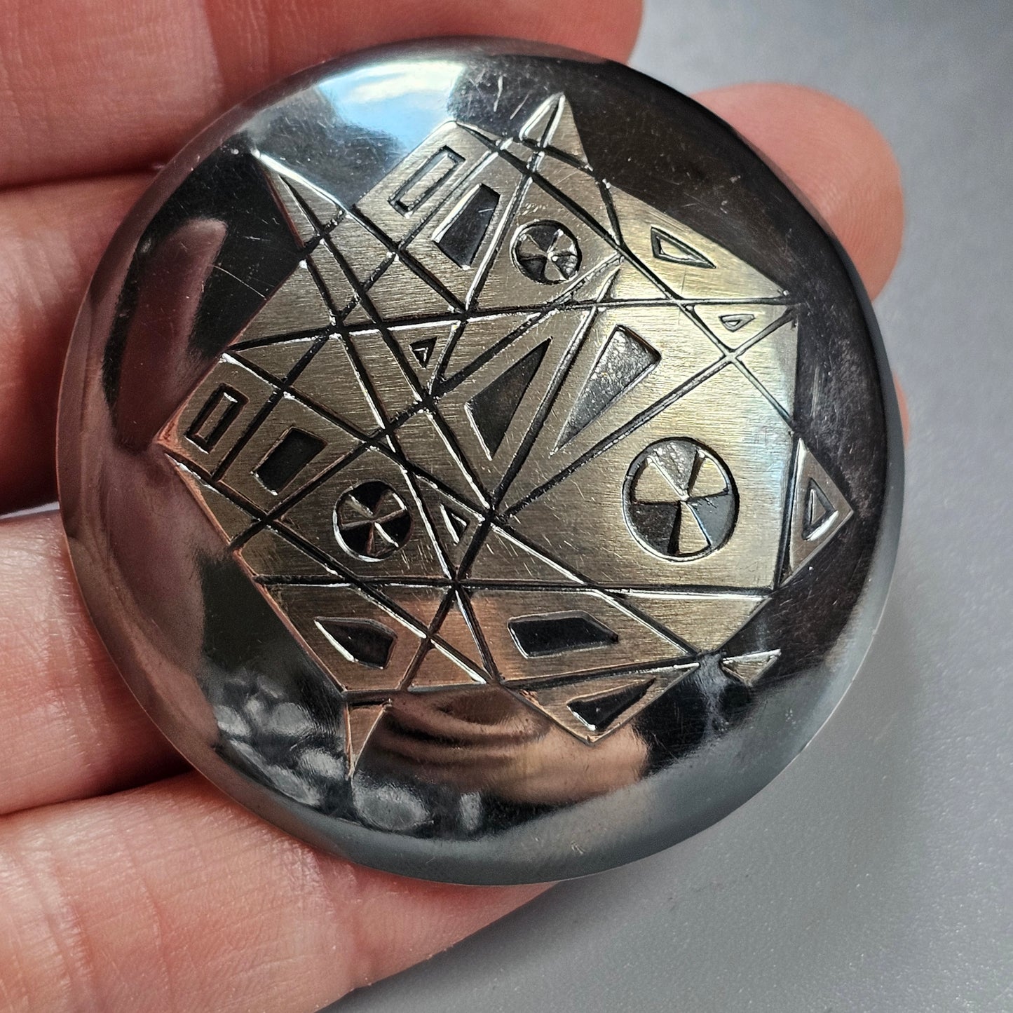 Metallic sphere with engraved geometric patterns and radiation symbols.