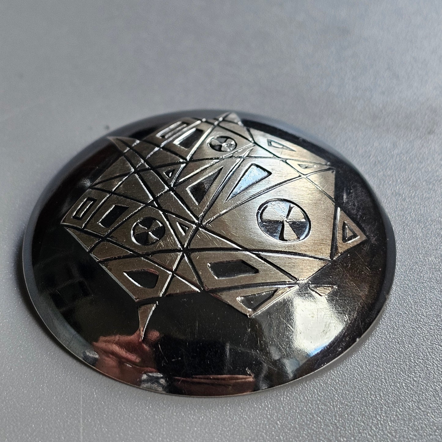 Metallic dome-shaped object with engraved geometric patterns and symbols.