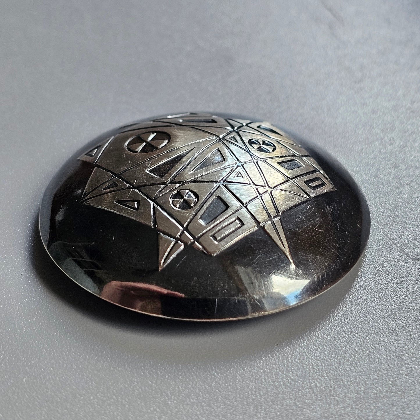 Metallic dome-shaped object with engraved geometric patterns.