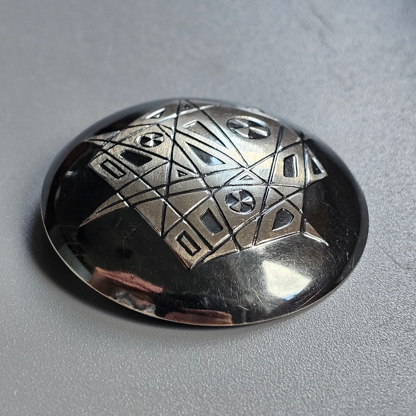 Metallic dome-shaped object with engraved geometric patterns.