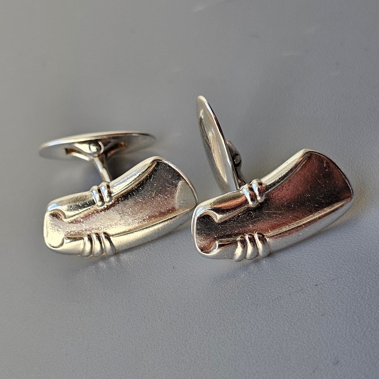 Pair of silver cufflinks shaped like golf clubs.