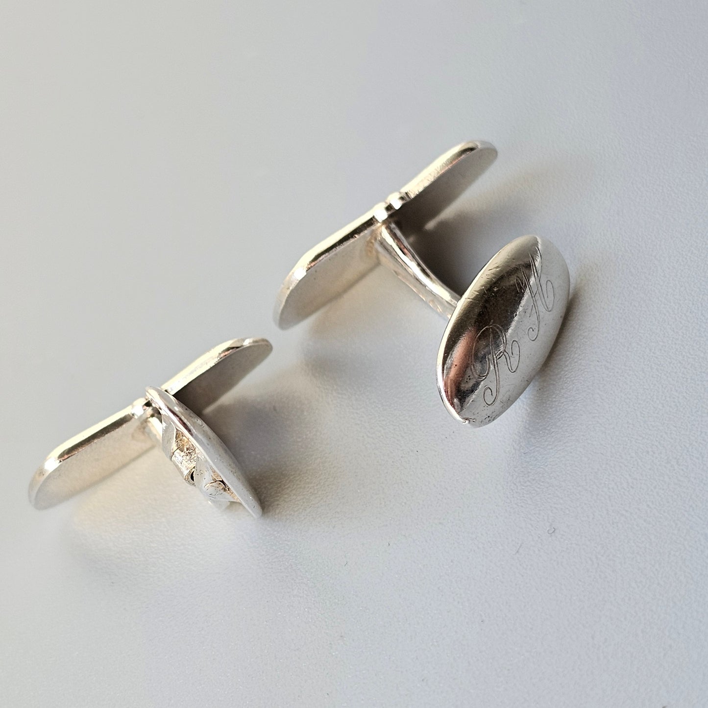 Pair of silver oval cufflinks with engraved designs.