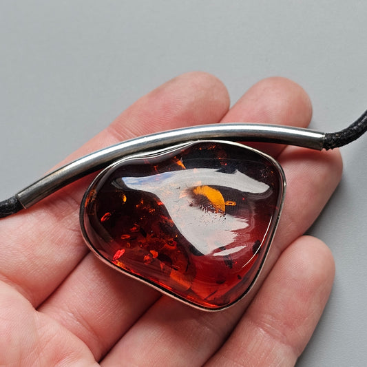 Amber pendant with an insect inclusion held in a person’s palm.