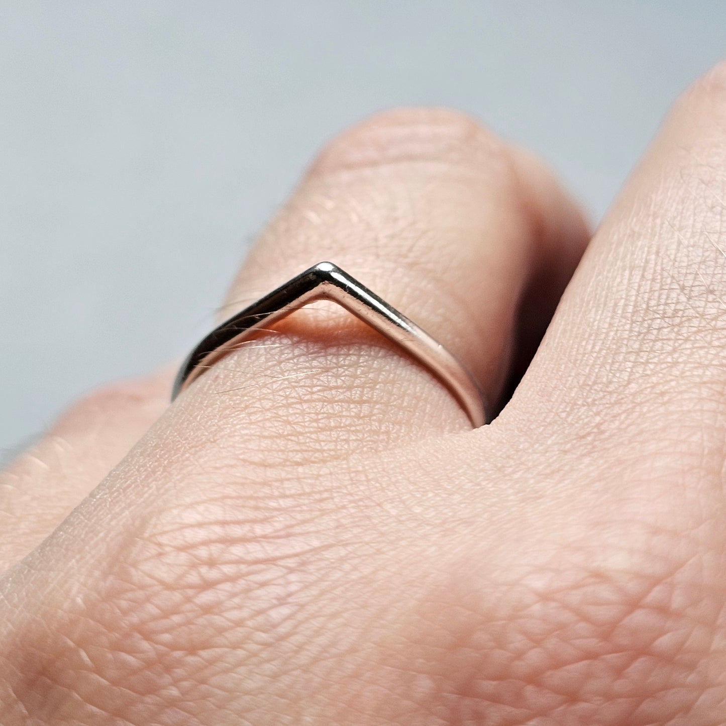 Delicate rose gold chevron ring worn on a finger.