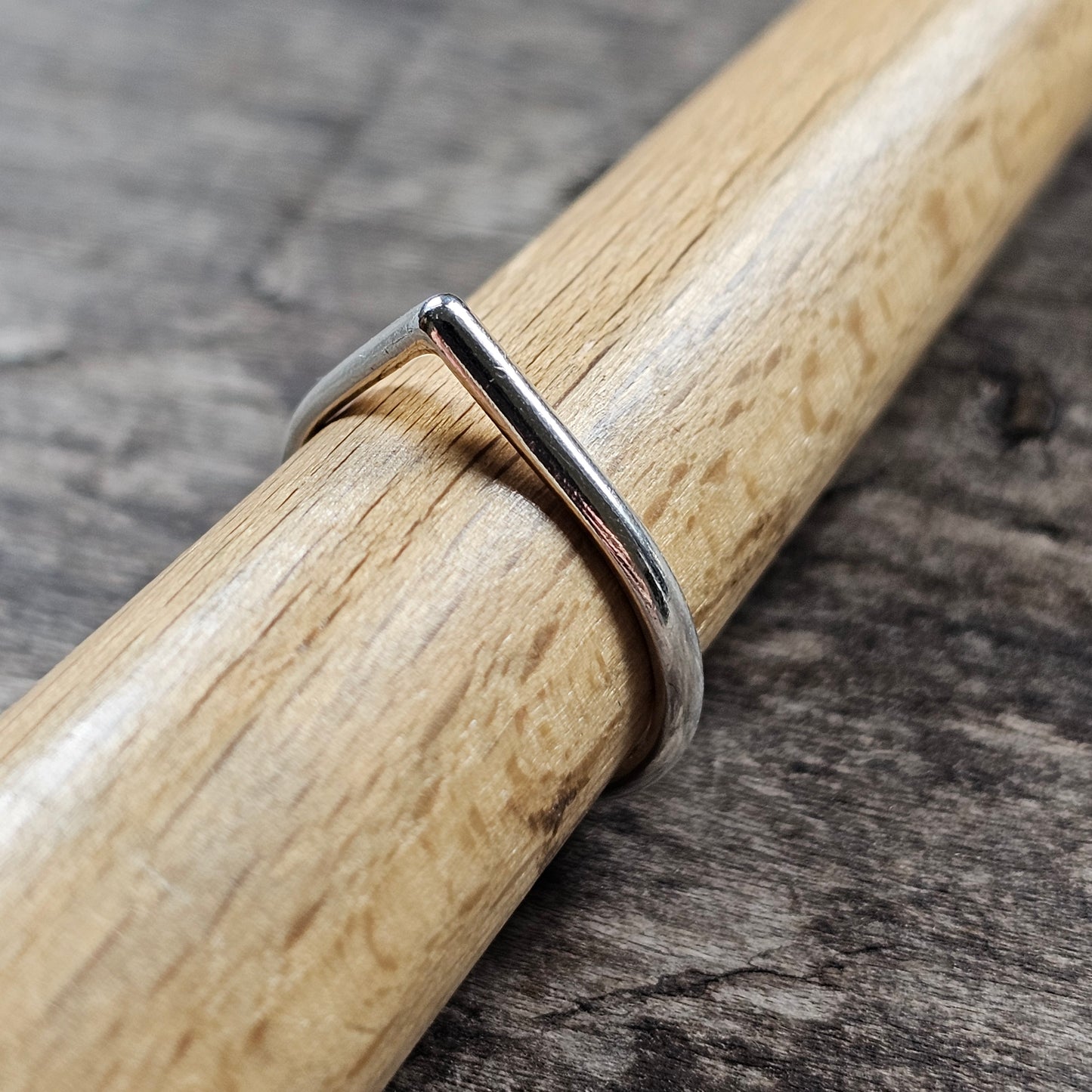 Simple silver ring wrapped around a wooden dowel or rod.