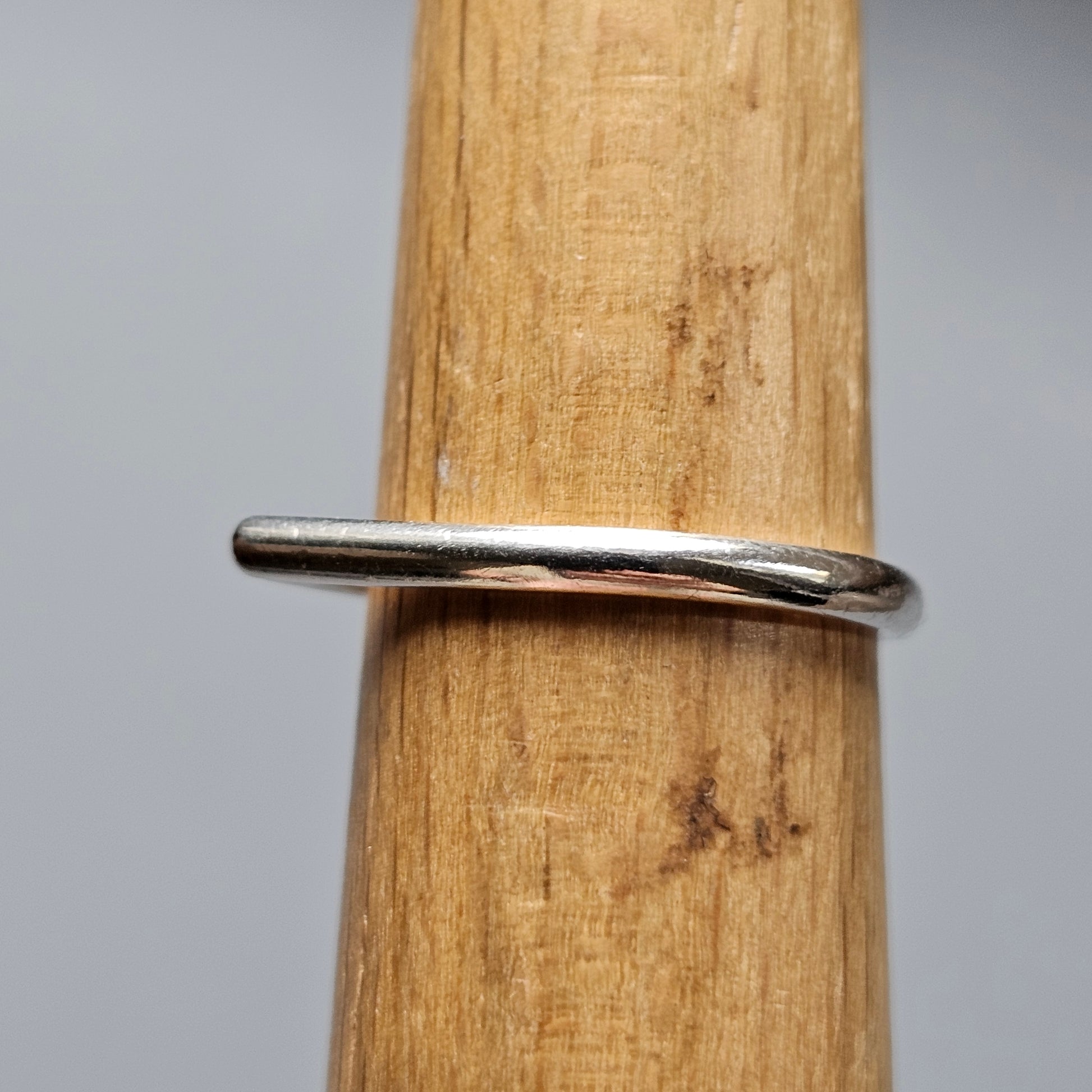 Simple silver ring on a wooden surface.