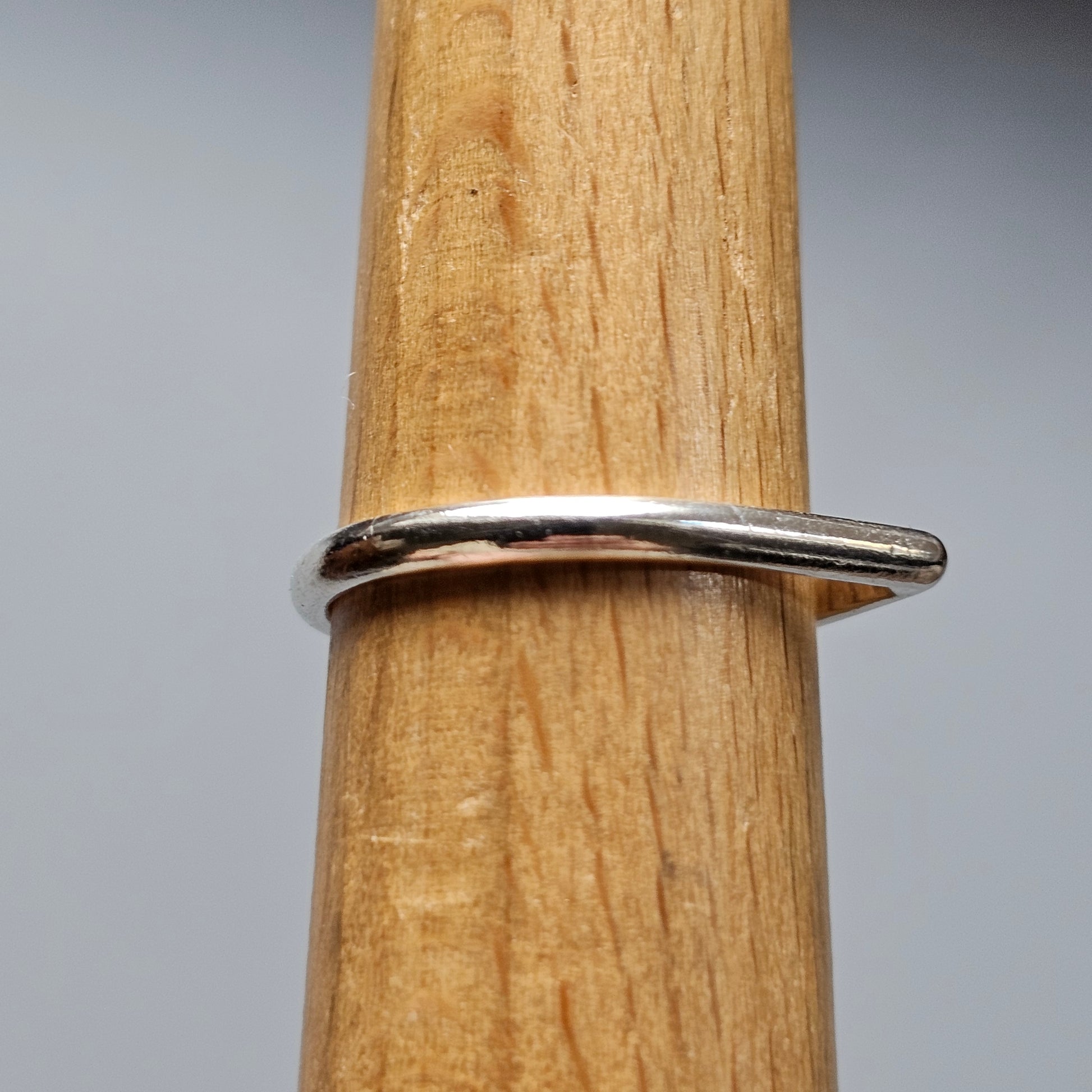 Simple silver ring encircling a wooden dowel or rod.