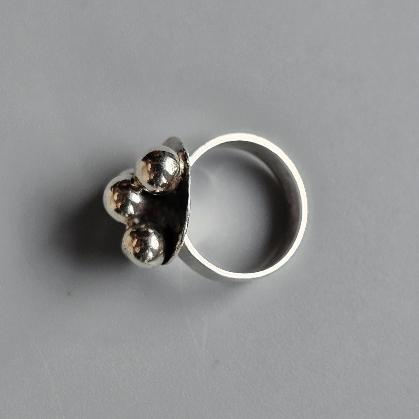 Silver ring with three metallic spheres attached to the band.