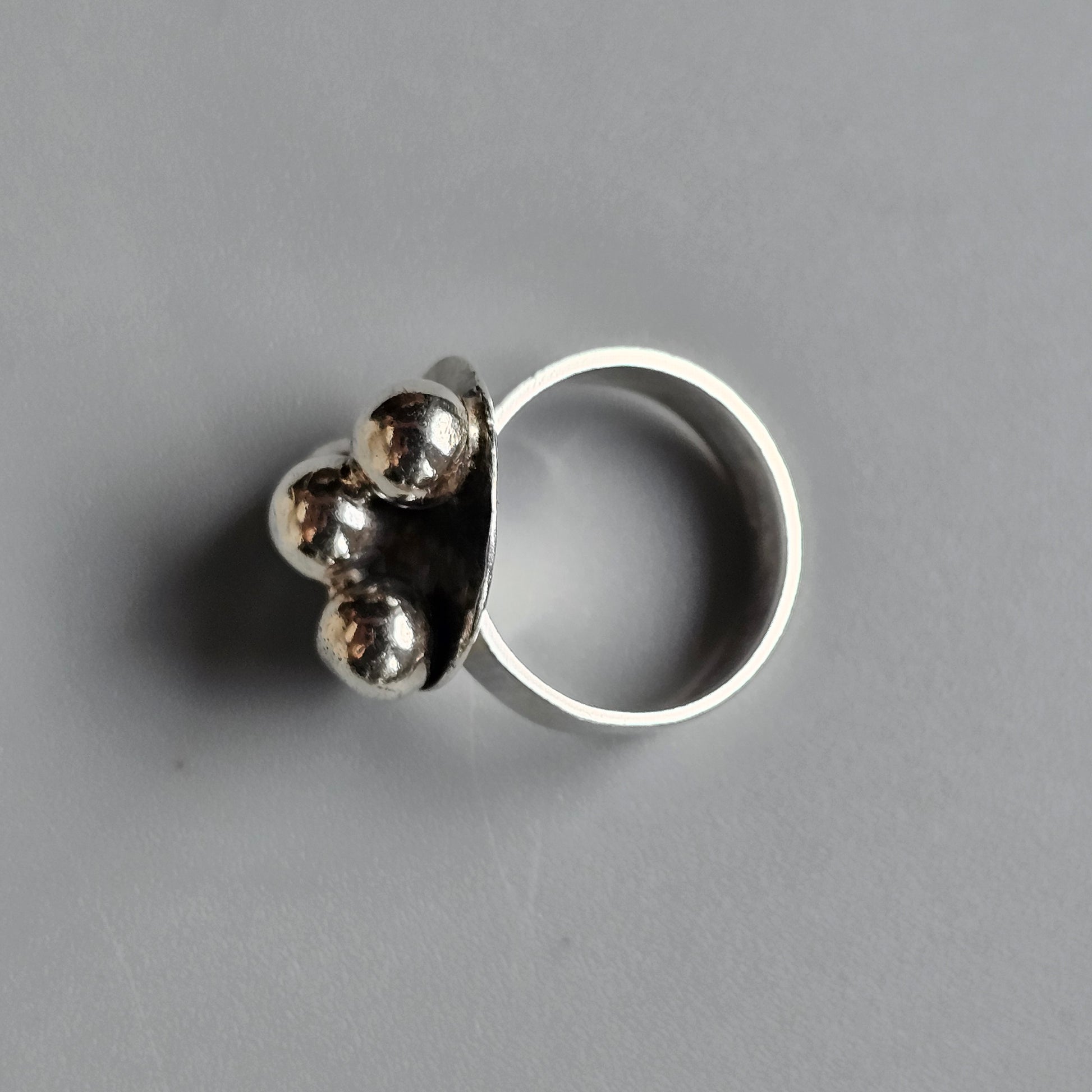 Silver ring with three metallic spheres attached to the band.