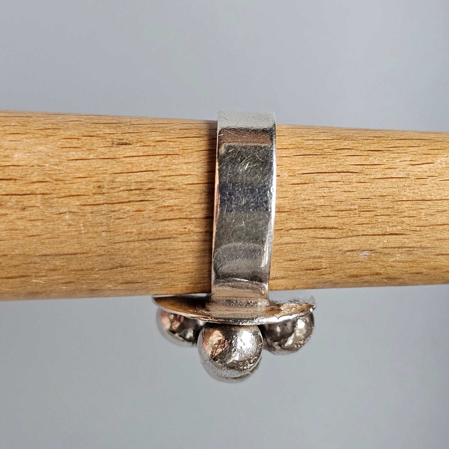 Silver ring with three spherical beads hanging from a band.